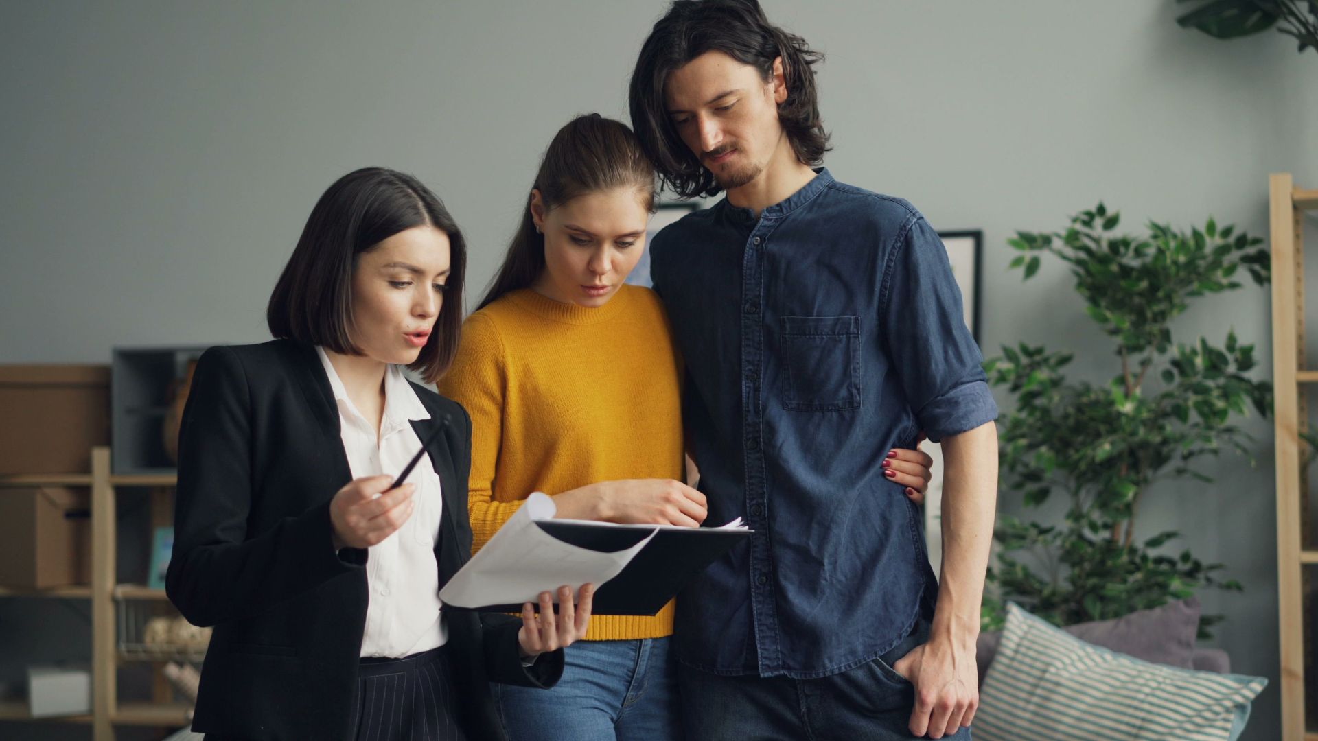 A couple reviewing documents with a real estate agent indoors.