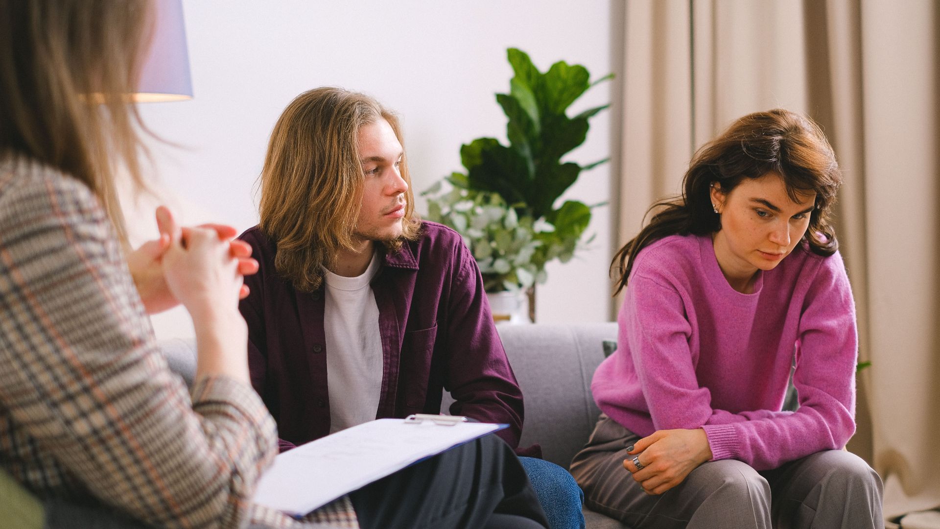 A couple engaged in a therapy session with a psychotherapist, discussing and reflecting indoors.