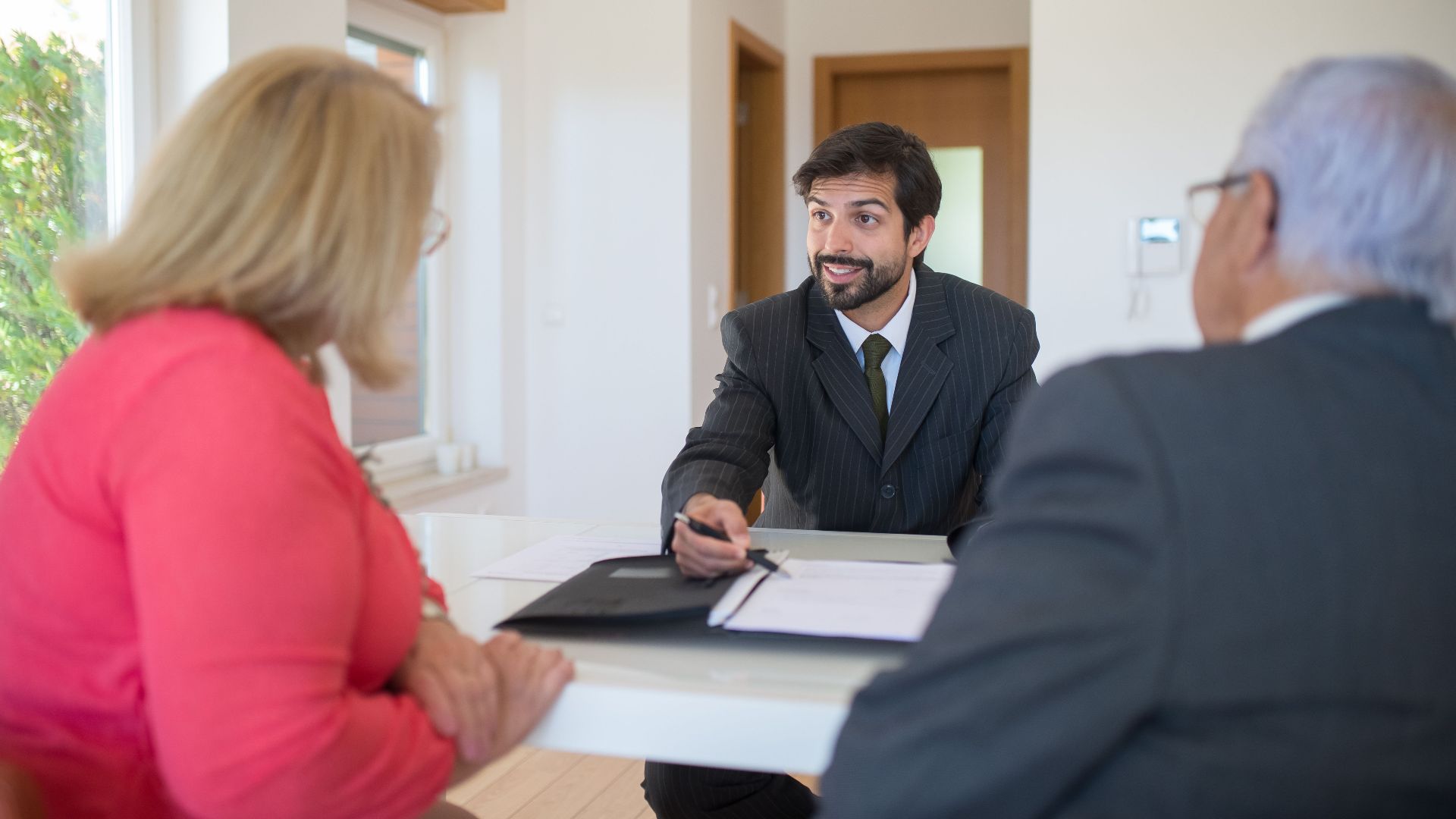 A real estate agent discussing a deal with senior clients in an office setting.