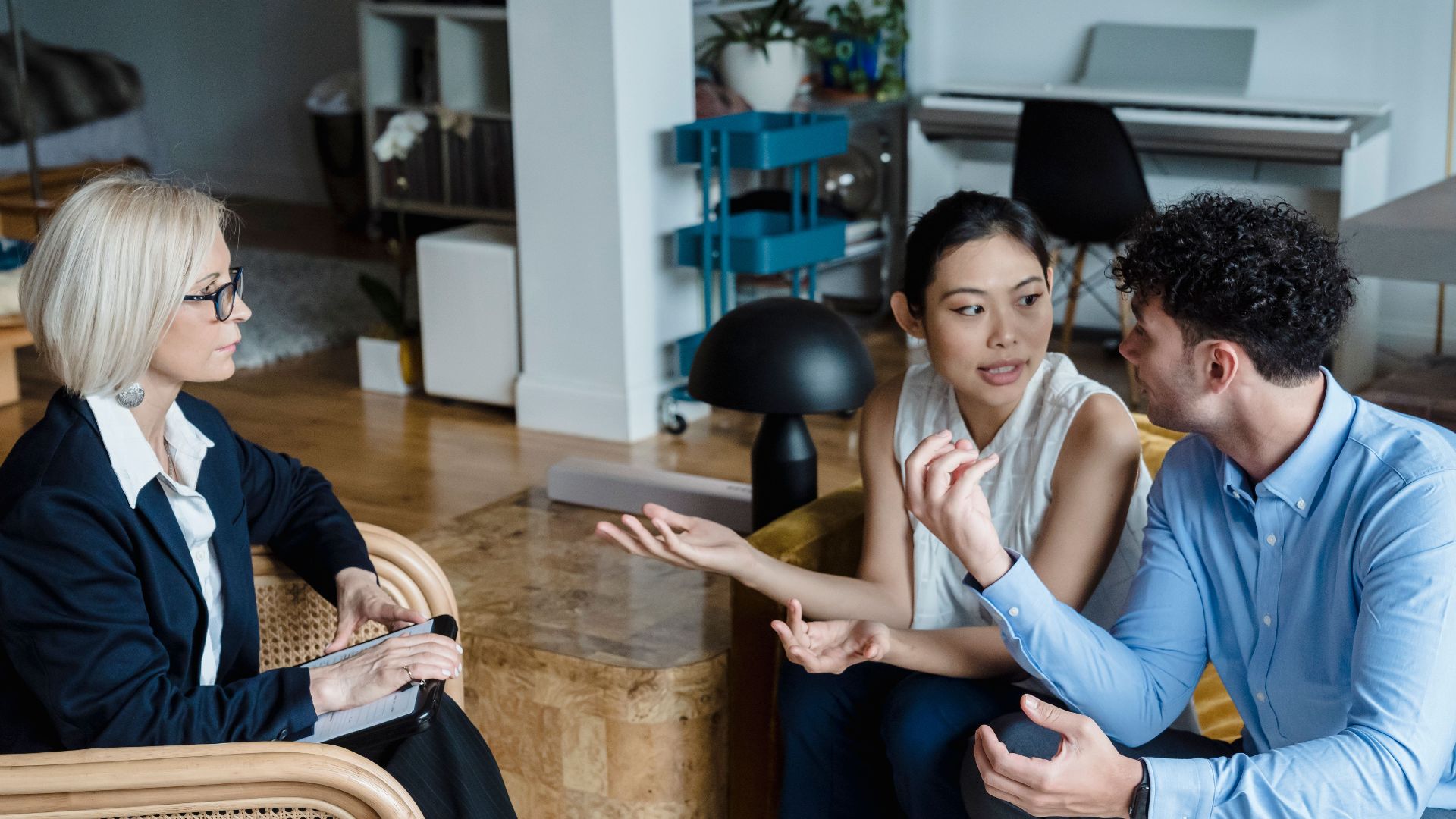 Couple having a discussion with a counselor in a modern living room setting.