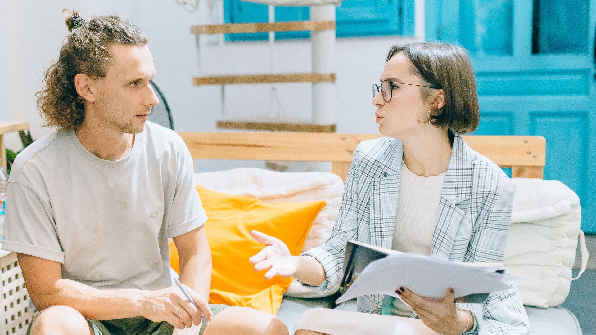 A man and woman discussing work in a stylish, bright living room setting.