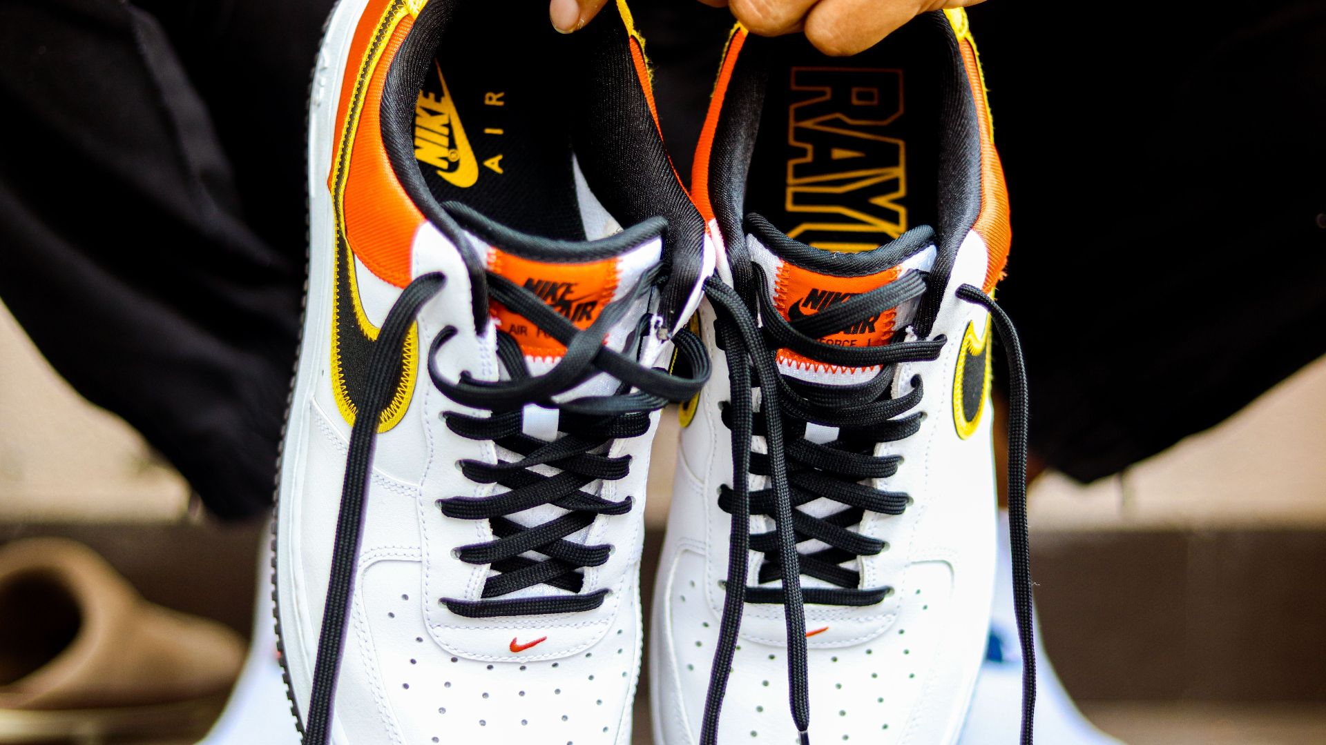 A detailed view of Nike Air Force 1 sneakers held by a person, showcasing design and style.
