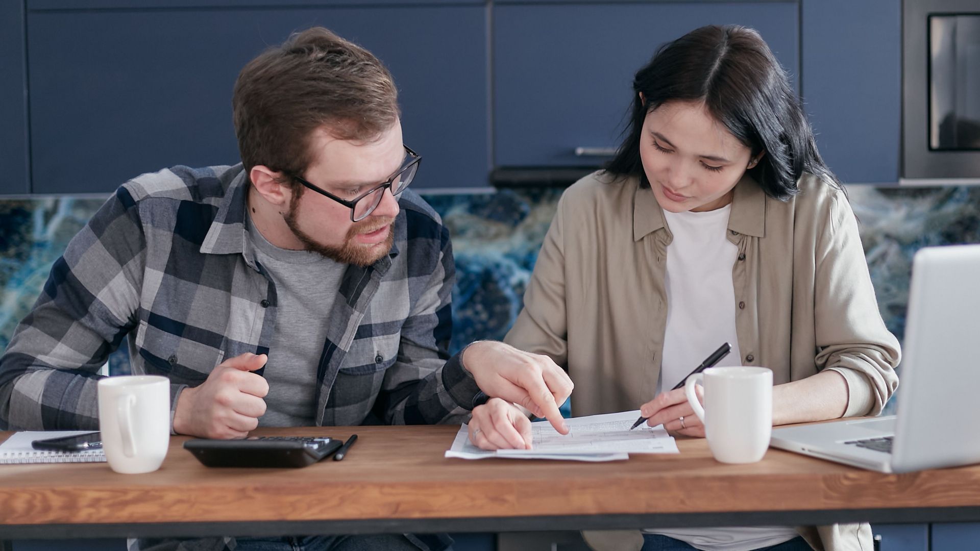 Interracial couple discussing bills and financial planning in a cozy indoor setting.