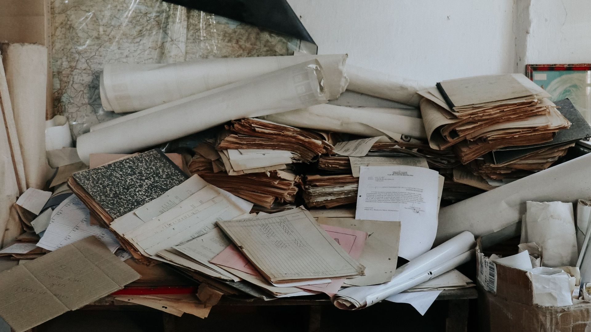 An abandoned desk piled with old papers and documents in a disorganized setting.