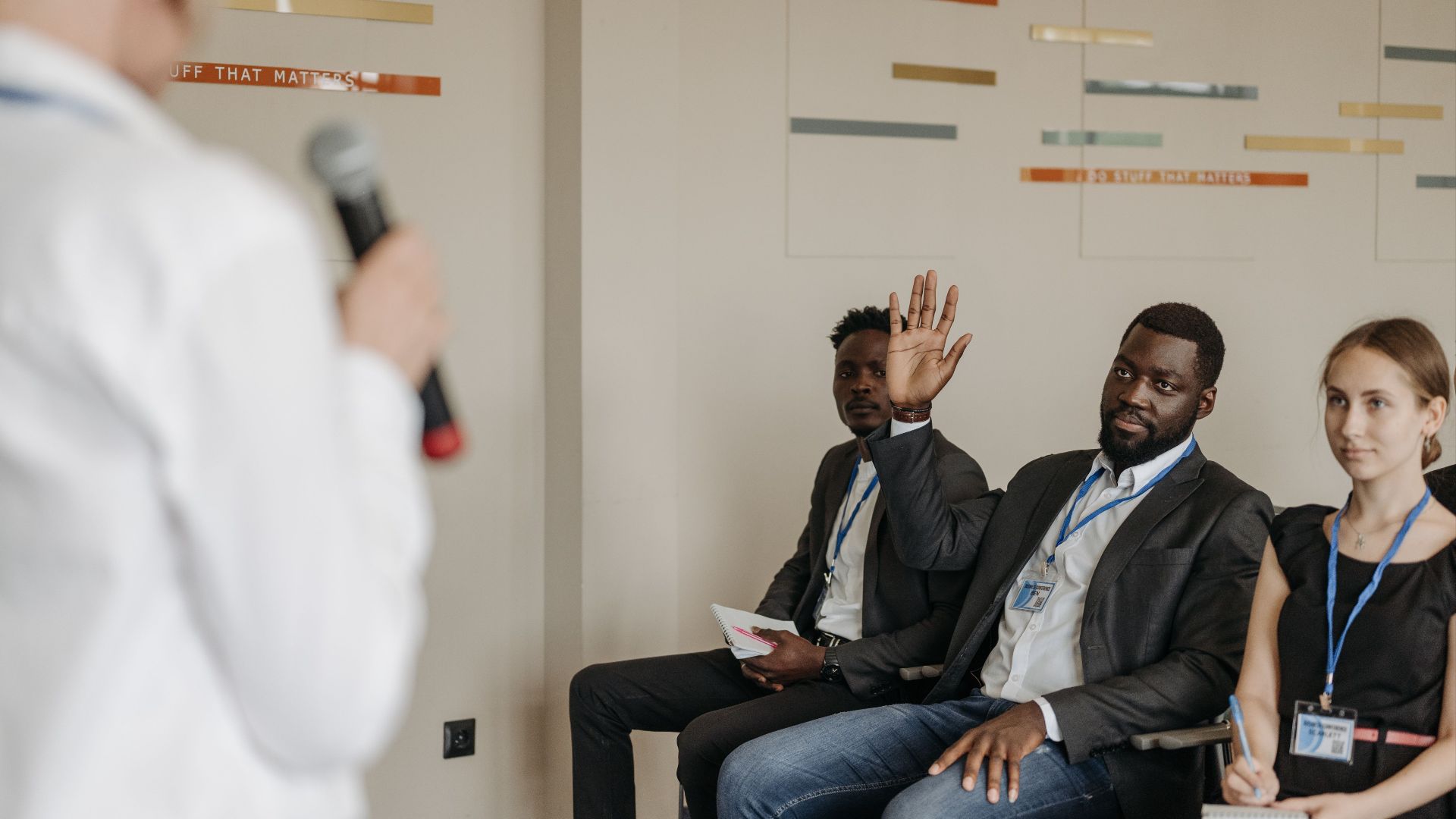 Engaged participants in a business conference, raising questions to the speaker.