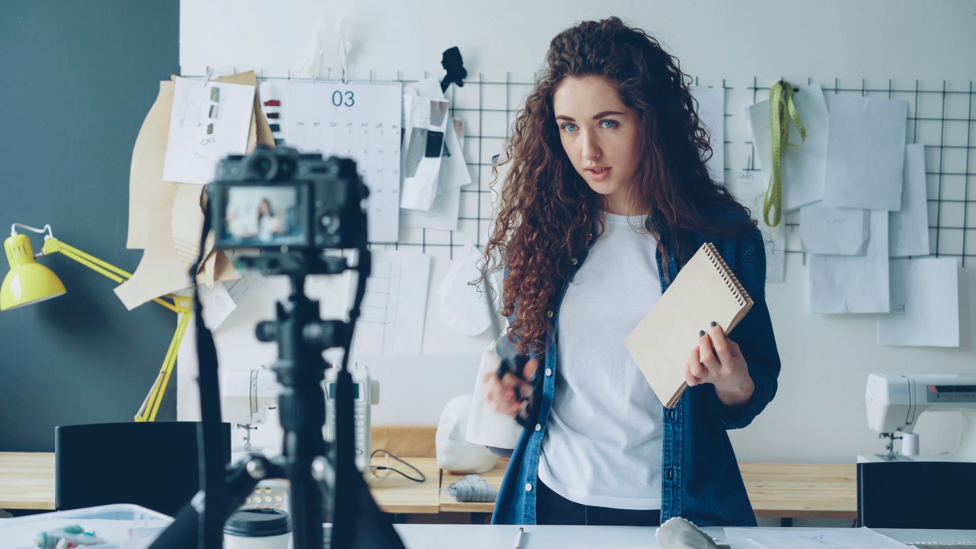 Young fashion designer records a video tutorial in her studio, focused on creativity and design.