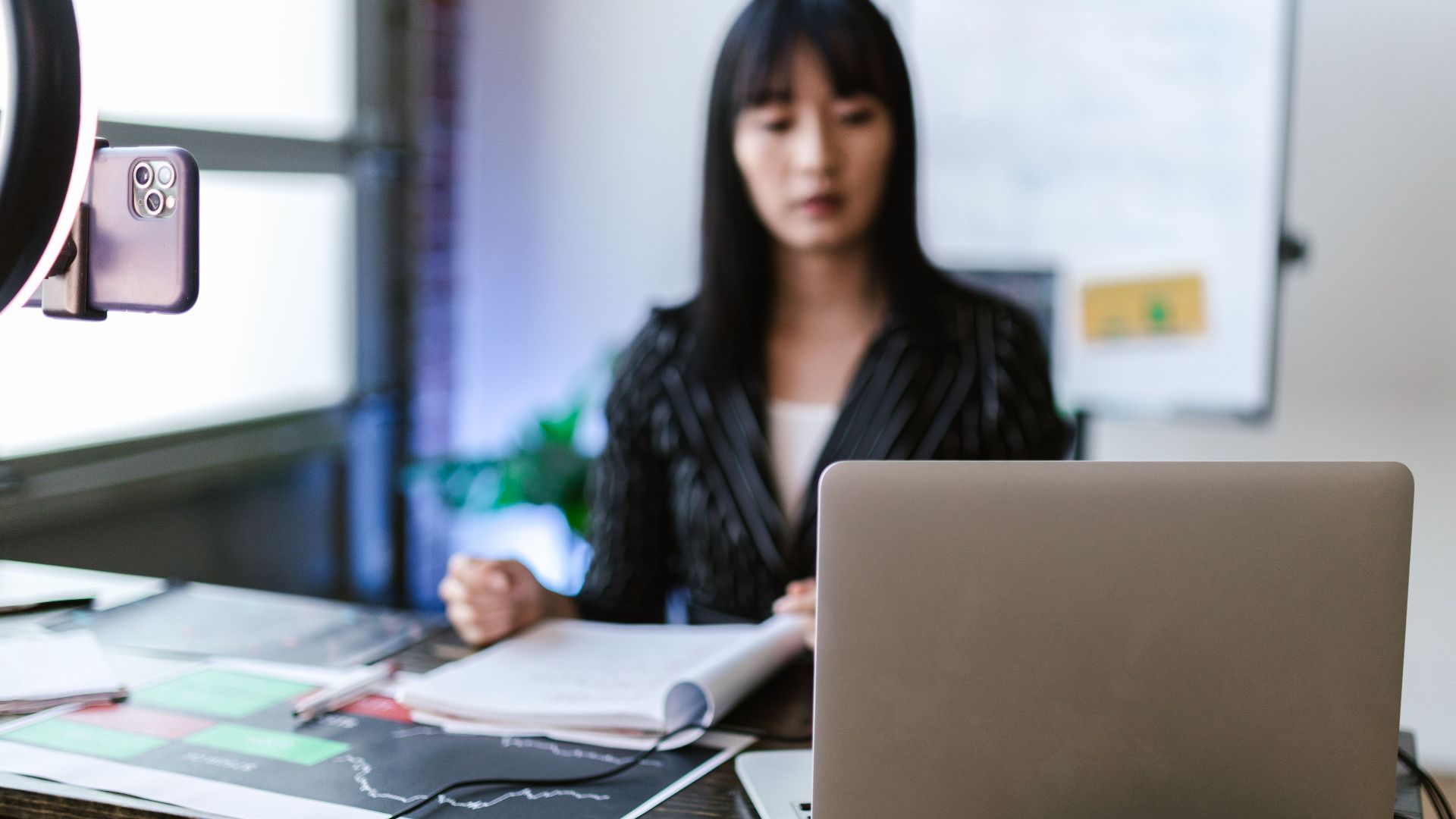 Focused woman trading stocks on a laptop in a modern office setting, capturing the essence of investment and technology.