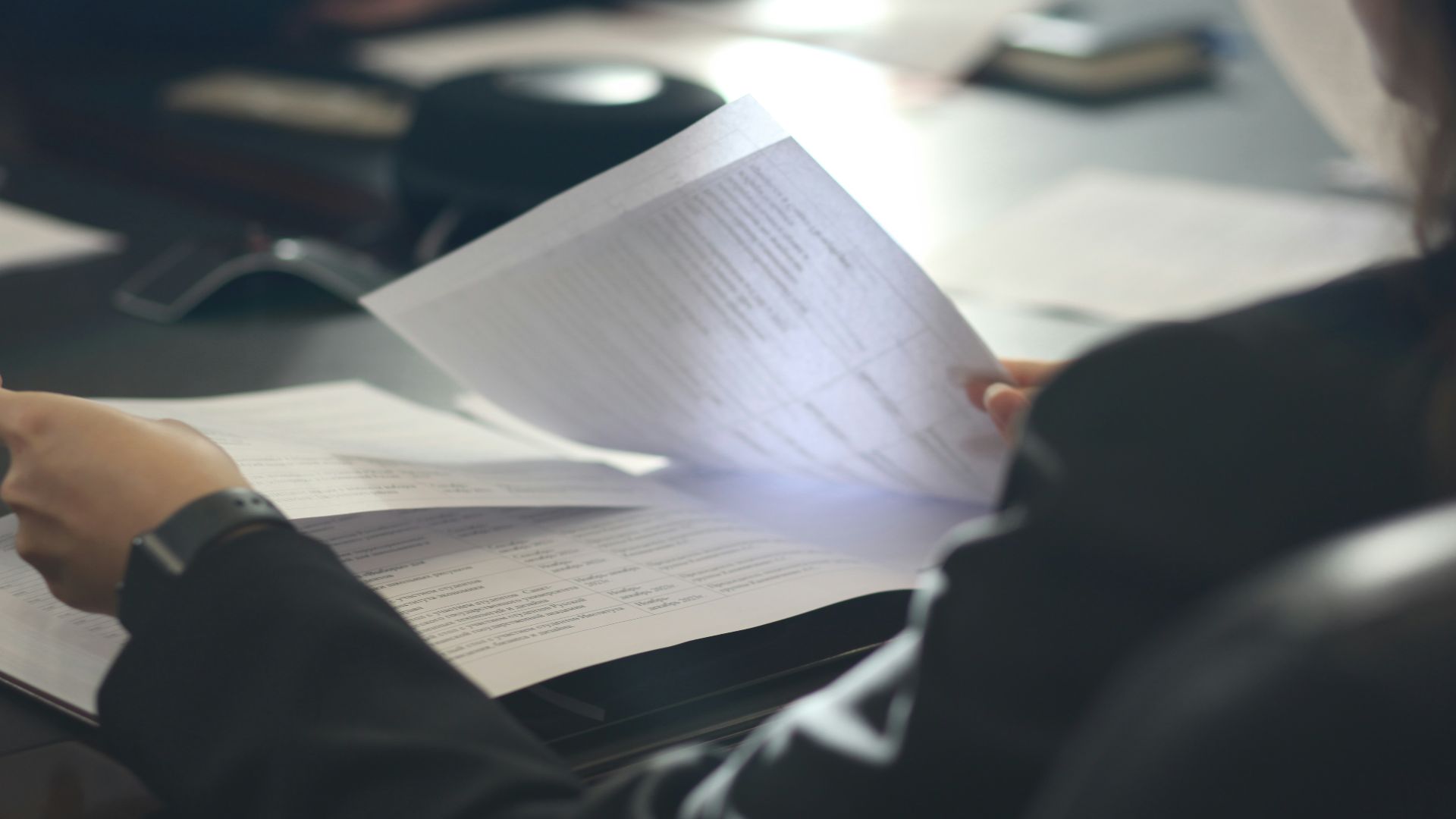 a woman sitting at a table reading a paper
