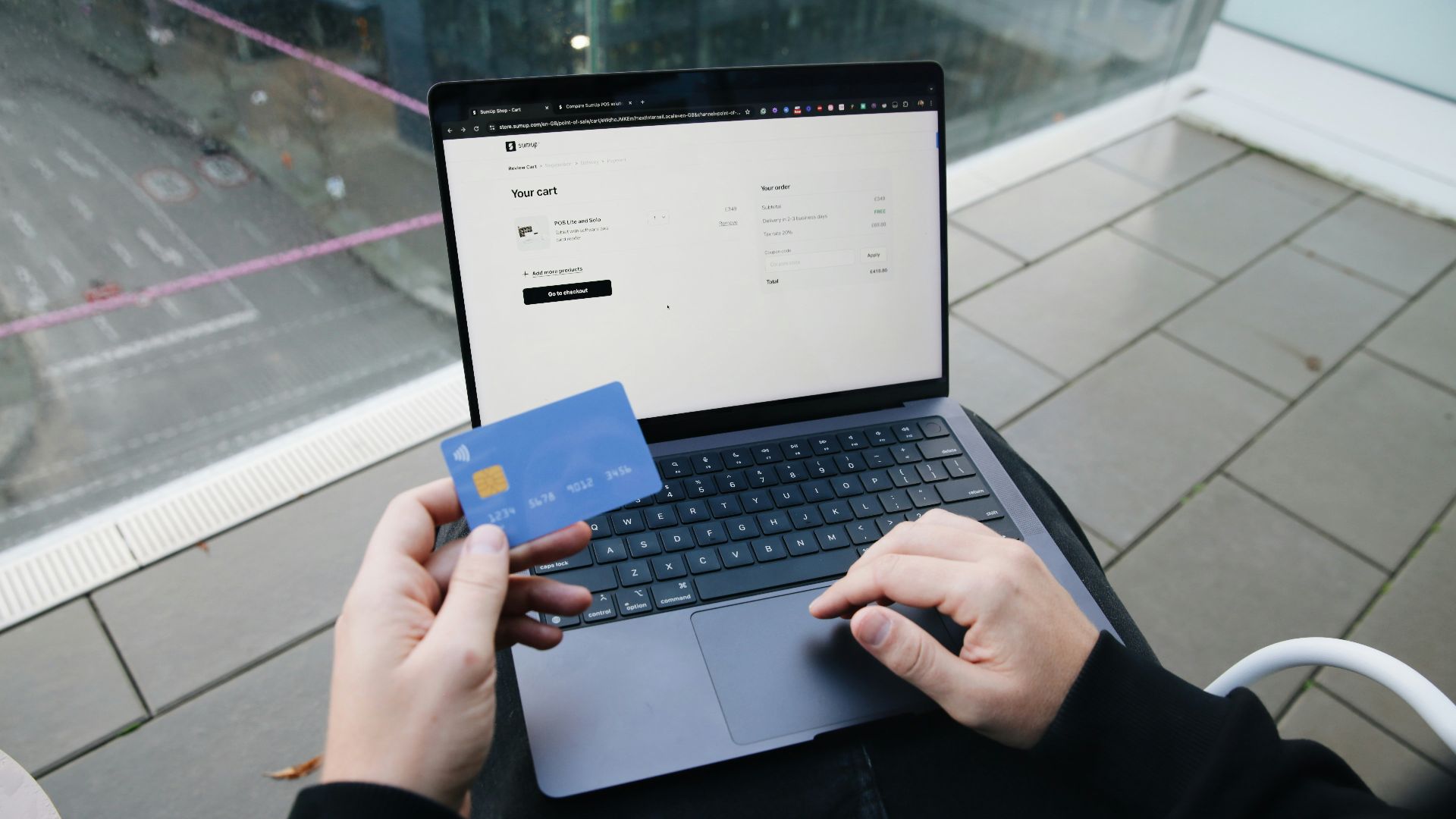 A person sitting in a chair with a laptop and a credit card