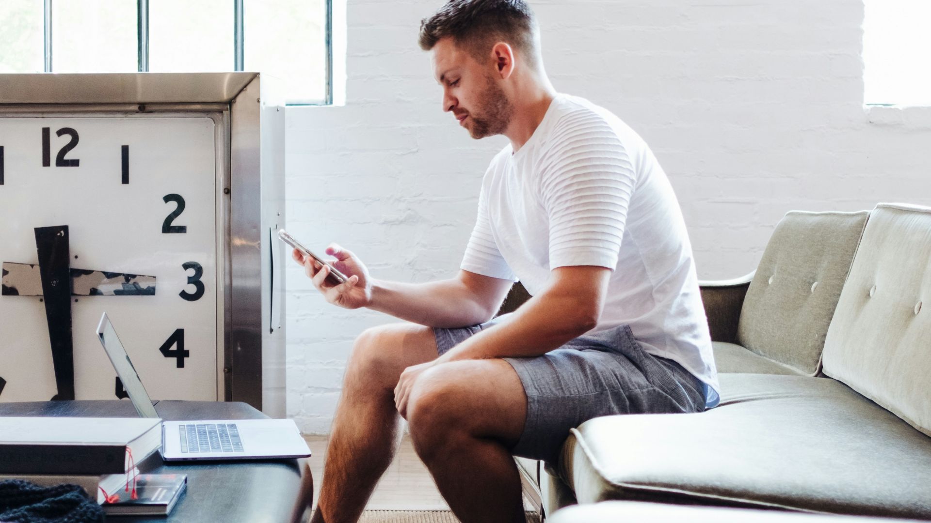 sitting man wearing white t-shirt using smartphone