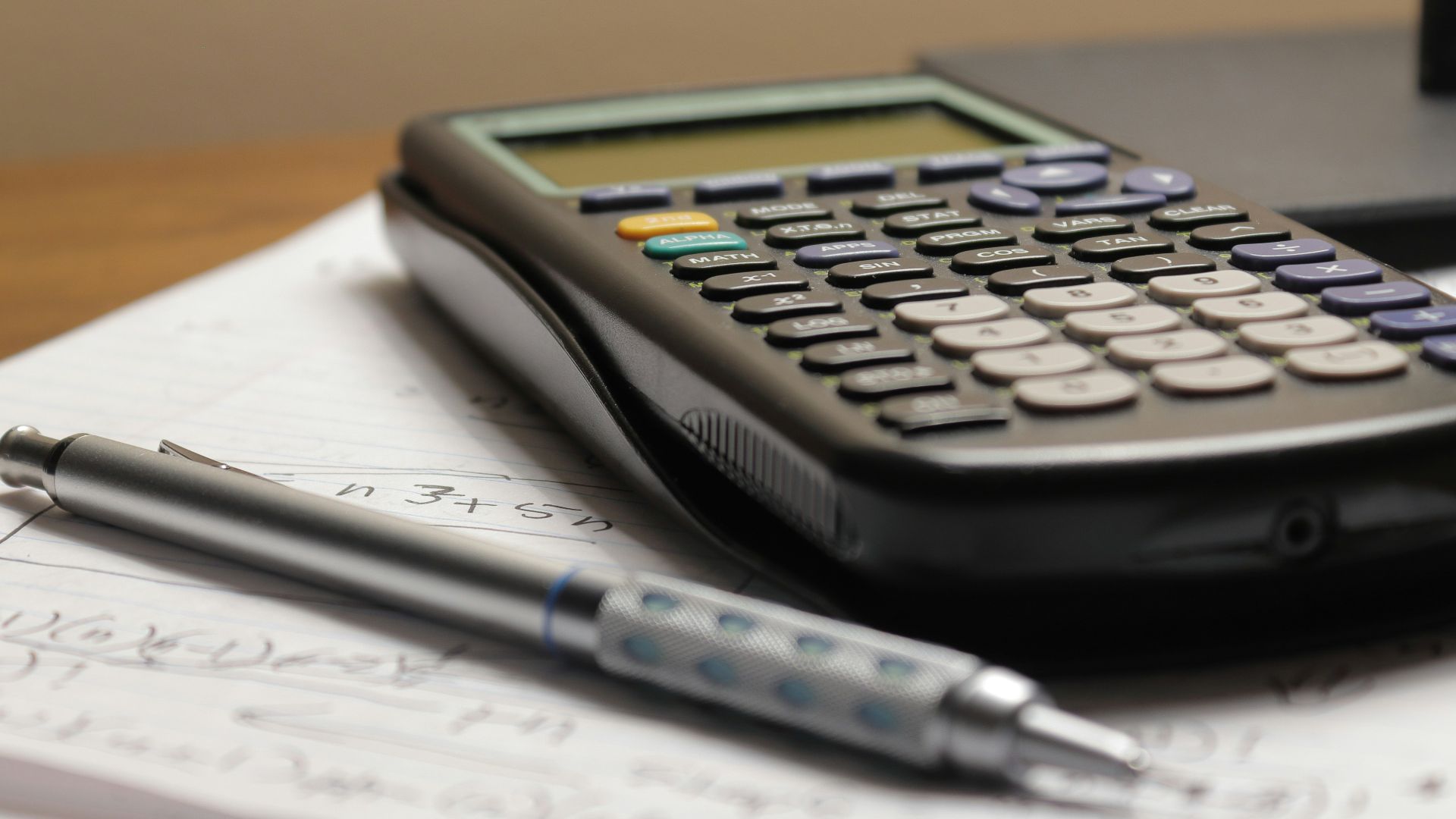 a calculator and a pen sitting on top of a piece of paper