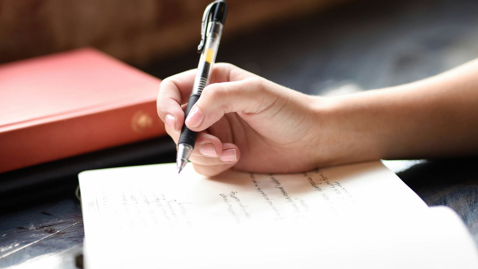 a person writing on a piece of paper with a pen