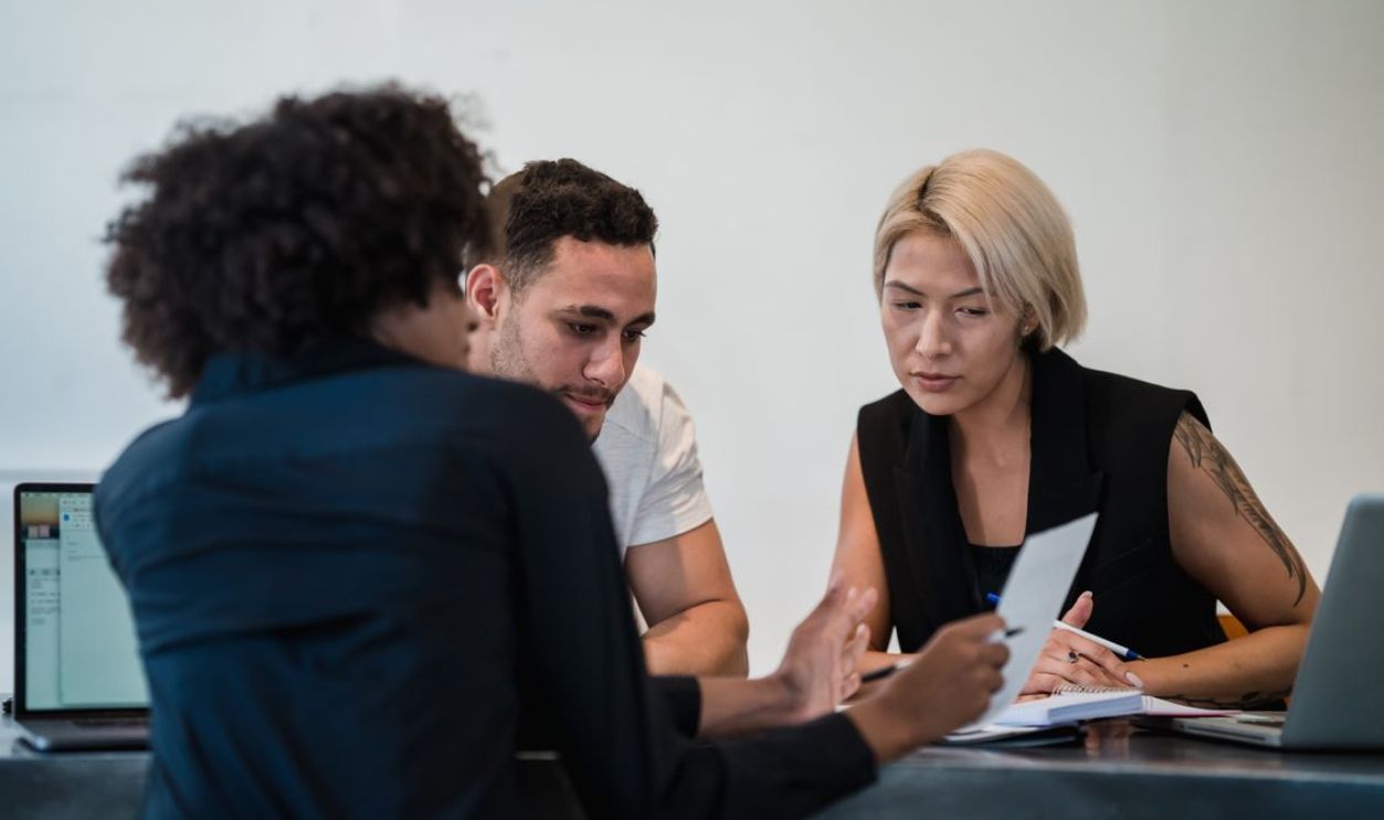 Diverse team engaged in a focused meeting at a contemporary workplace, discussing project details.