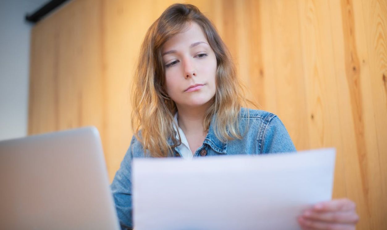 Businesswoman in a denim jacket analyzing documents at a wooden table in a cozy workspace