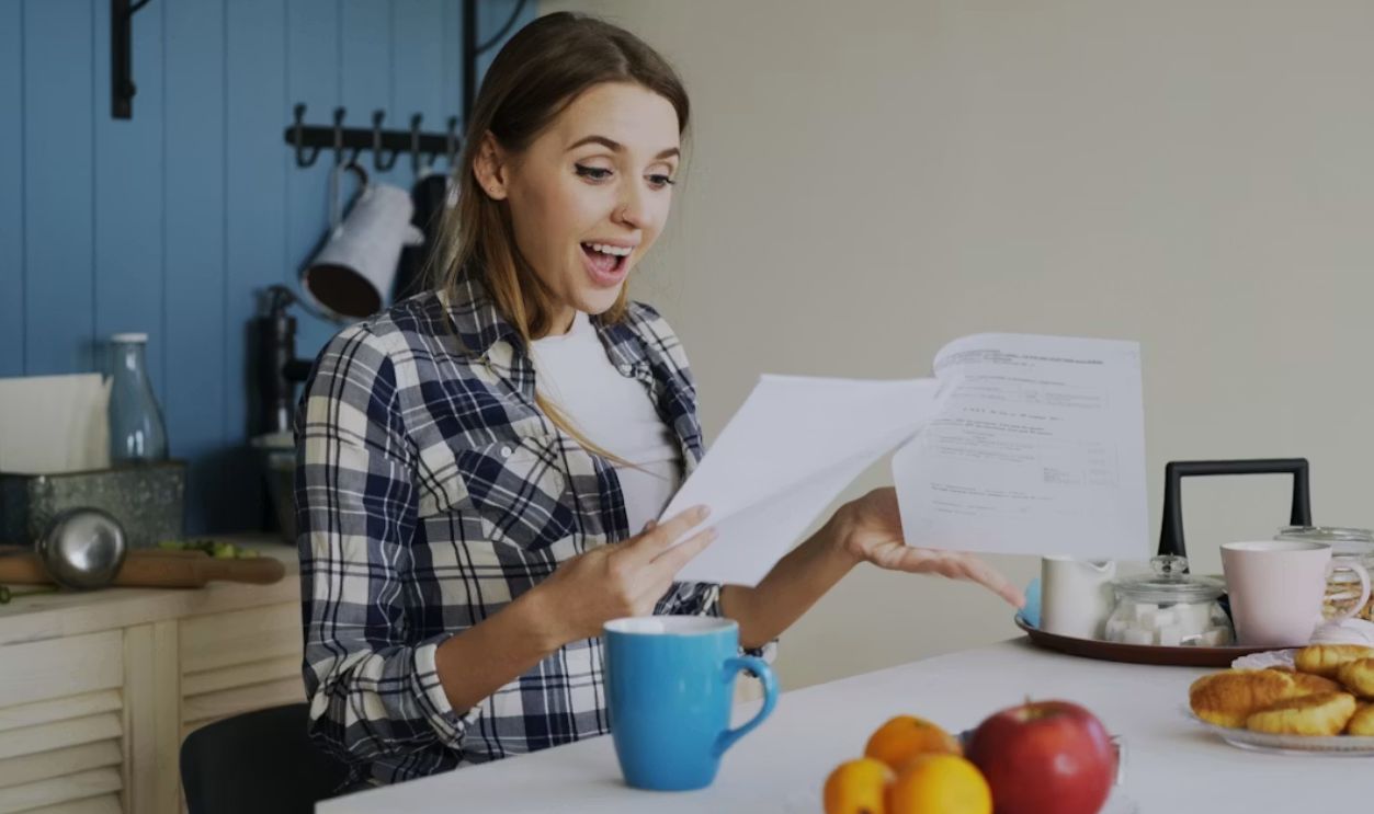 Woman with surprised expression reading documents at table