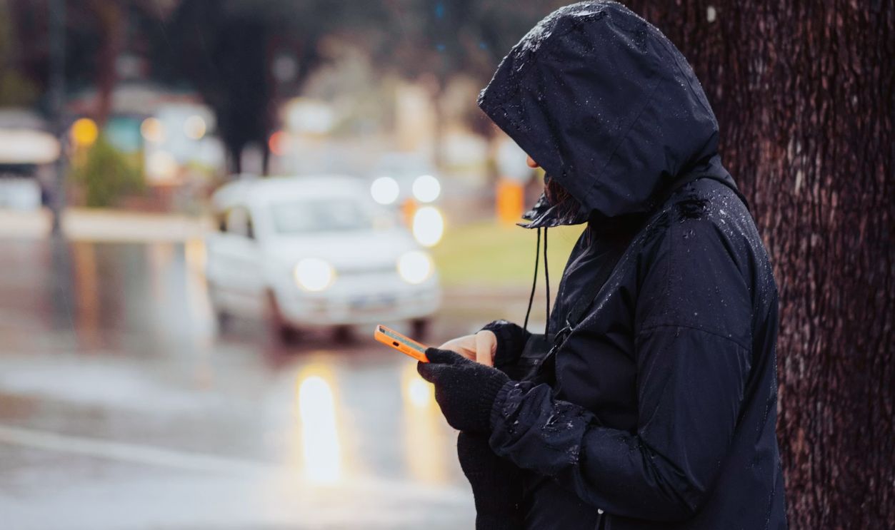 a person standing next to a tree using a cell phone
