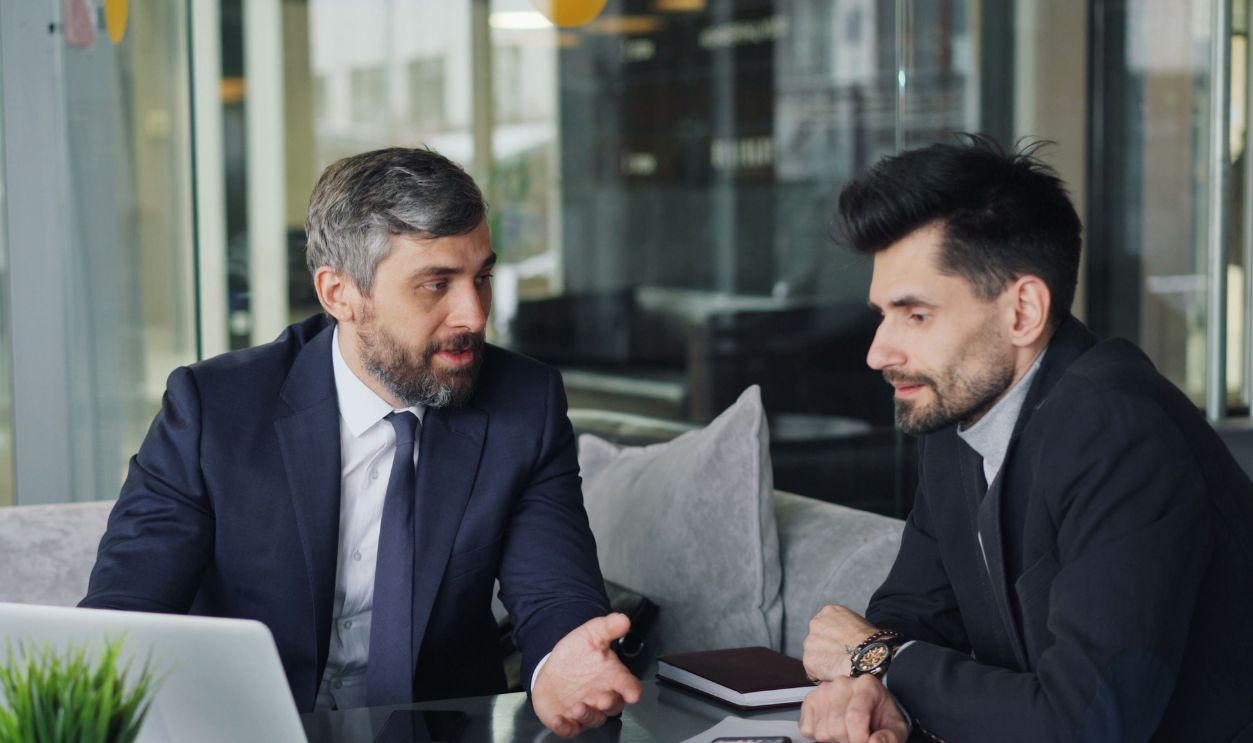 Two businessmen in a café having a professional discussion with coffee 