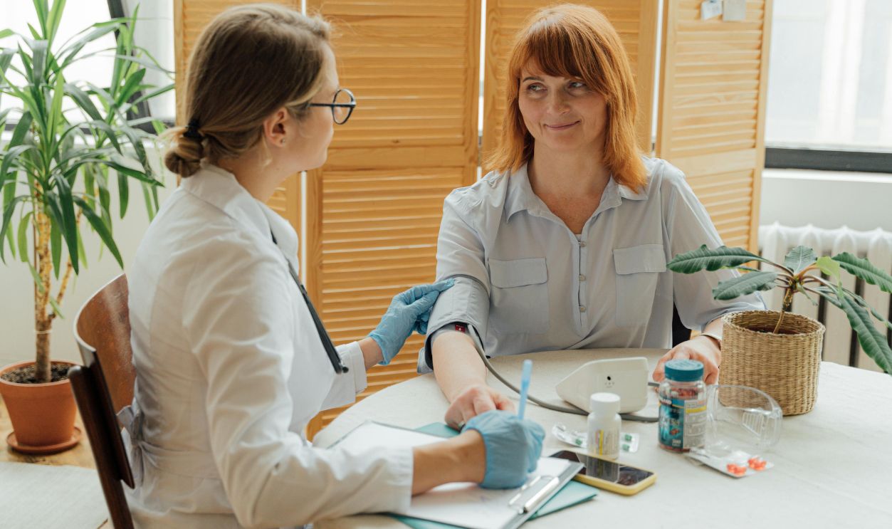 Doctor measuring patient's blood pressure with digital monitor in a clinical setting