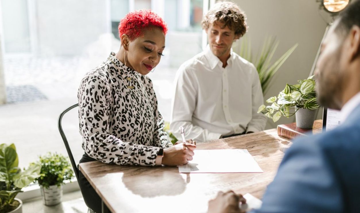 A professional signing documents during a meeting in a modern office space