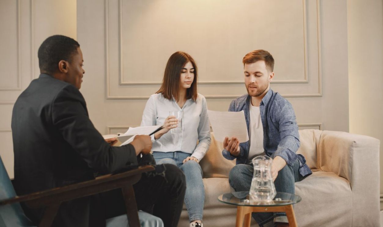 Therapist counseling couple with documents in contemporary office setting