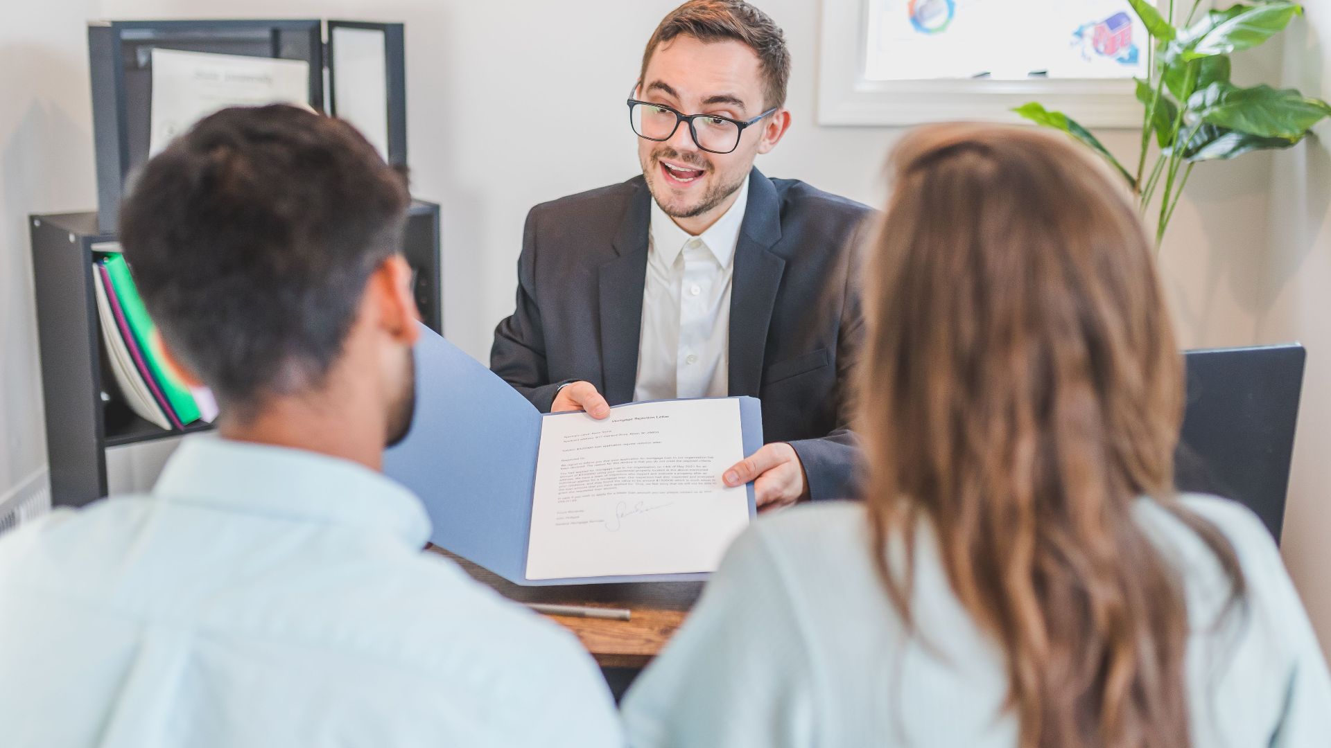 A businessman discusses a contract with clients in a modern office setting.