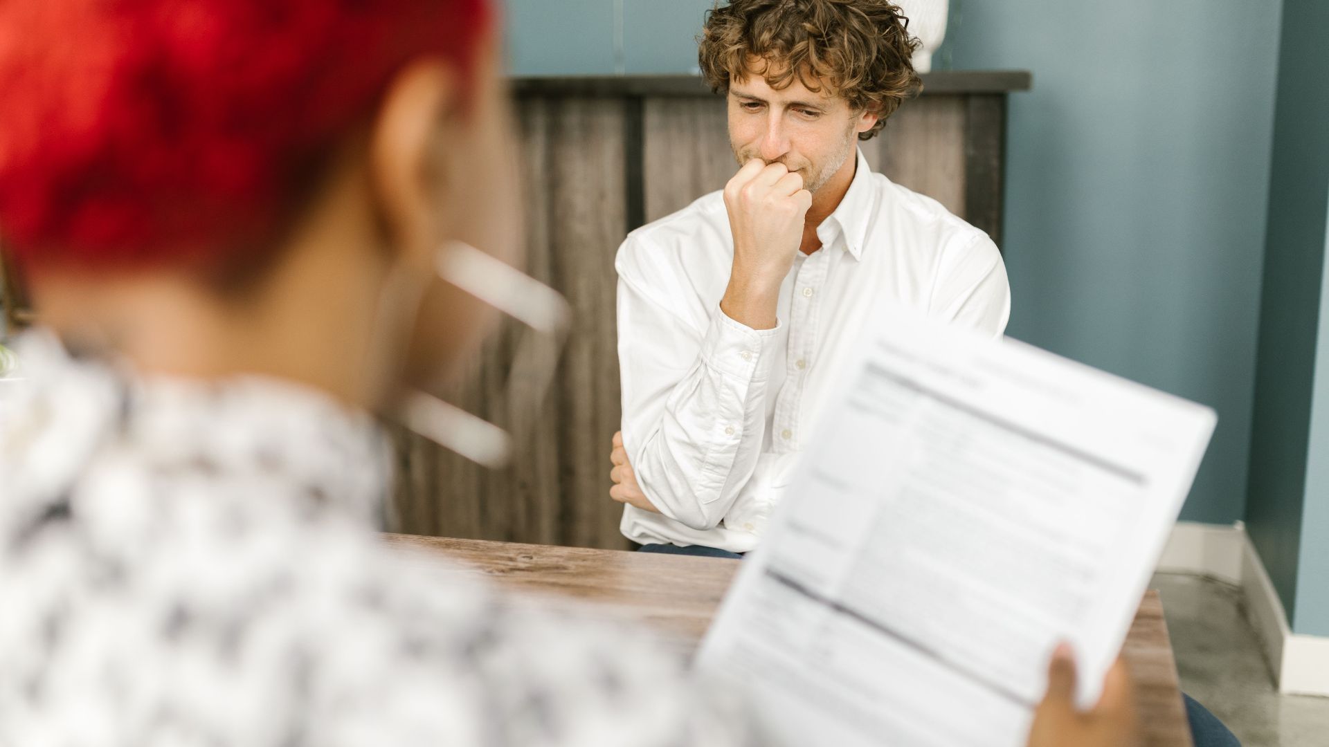 Man reflecting during a job interview in an office setting, highlighting thoughtfulness.