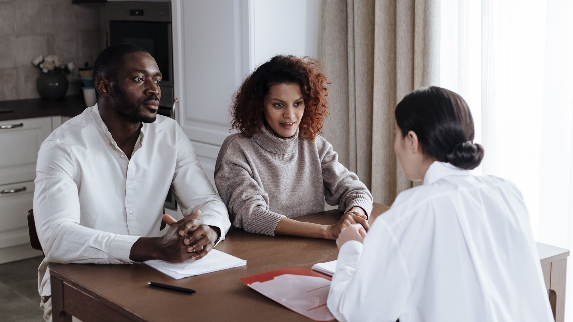 Man and woman discussing documents with a social worker at home.