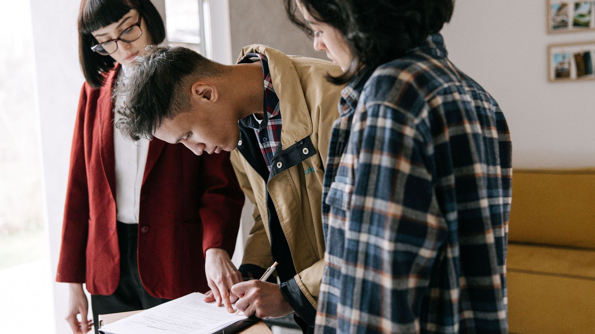 Young couple signing a real estate agreement with an agent indoors.