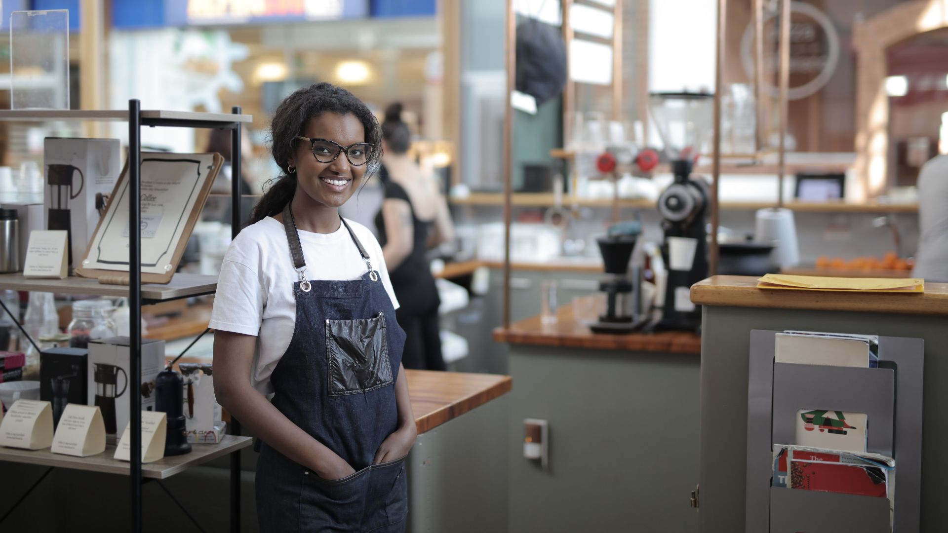 Smiling barista standing in a stylish café, showcasing entrepreneurial spirit.