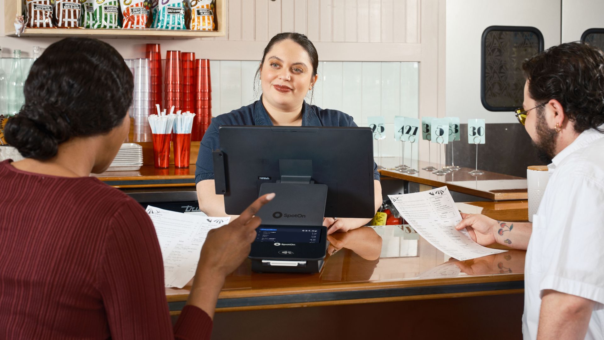 Restaurant staff take orders at a POS system, showcasing modern dining technology.