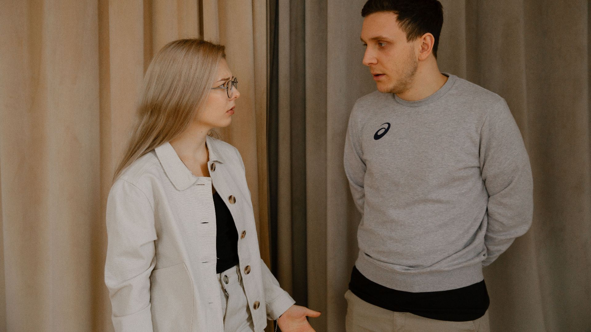 Man and woman having a serious conversation indoors, focused expressions.