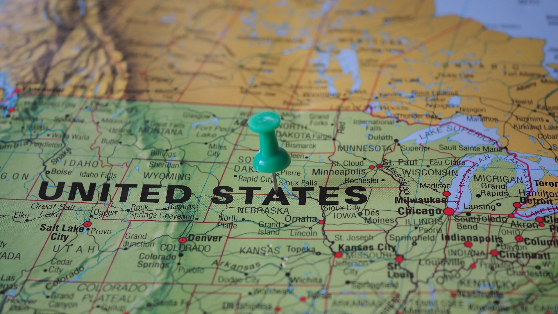 High-angle view of a map featuring the United States with a green pin indicating a specific location.