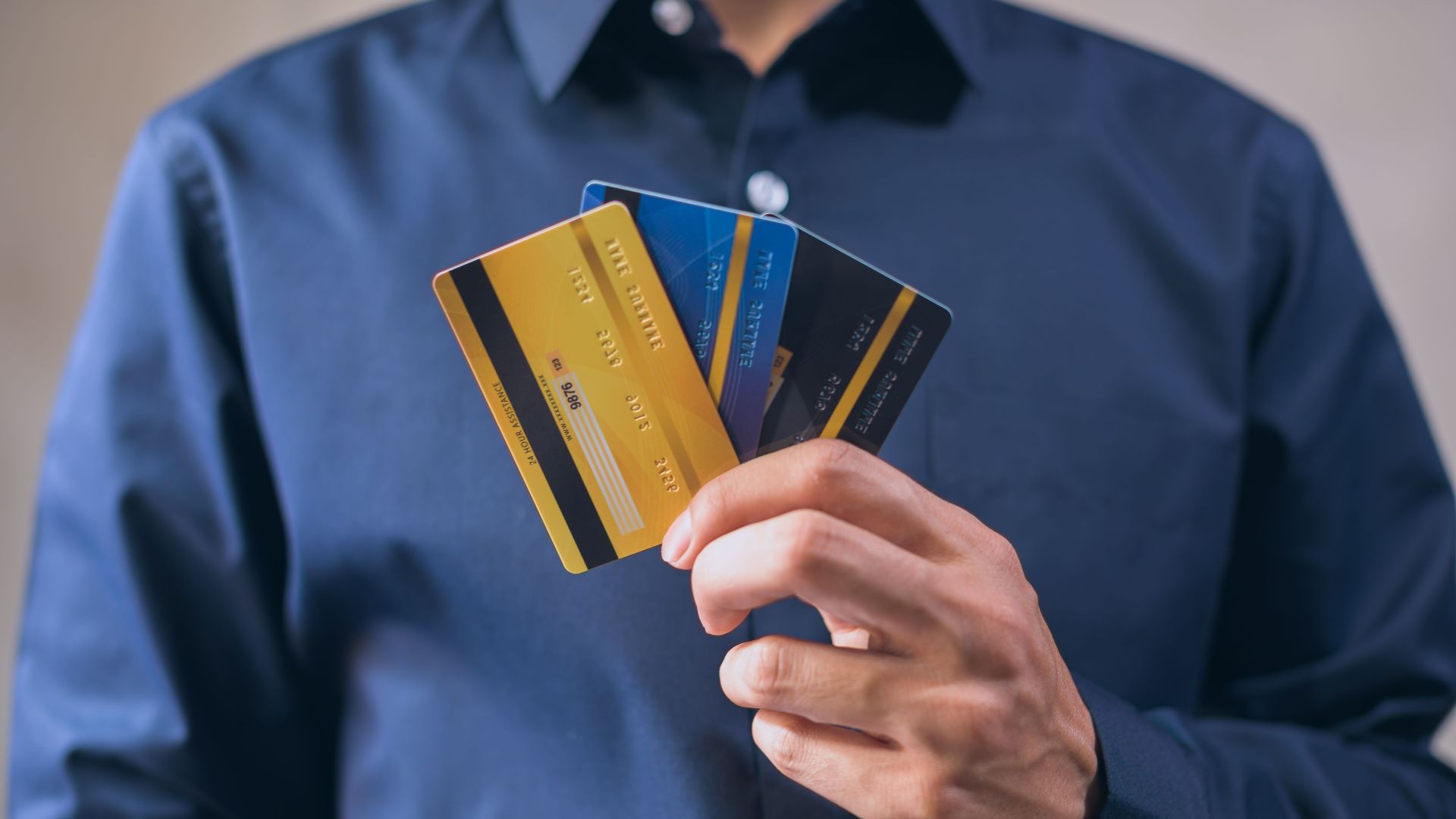 Person holding three credit cards, symbolizing finance, security, and e-commerce.