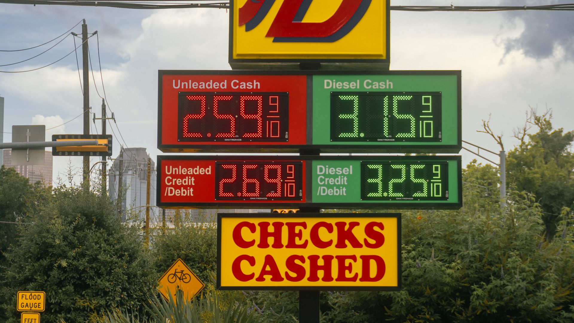 Gas station signboard displaying fuel prices and checks cashed in Houston, TX.