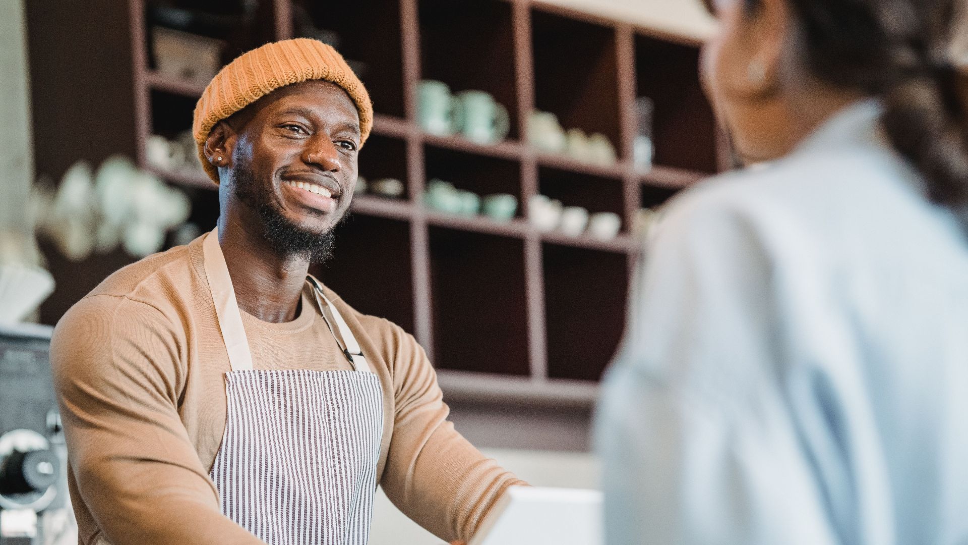 A smiling barista taking an order from a customer at a café counter, creating a warm atmosphere.
