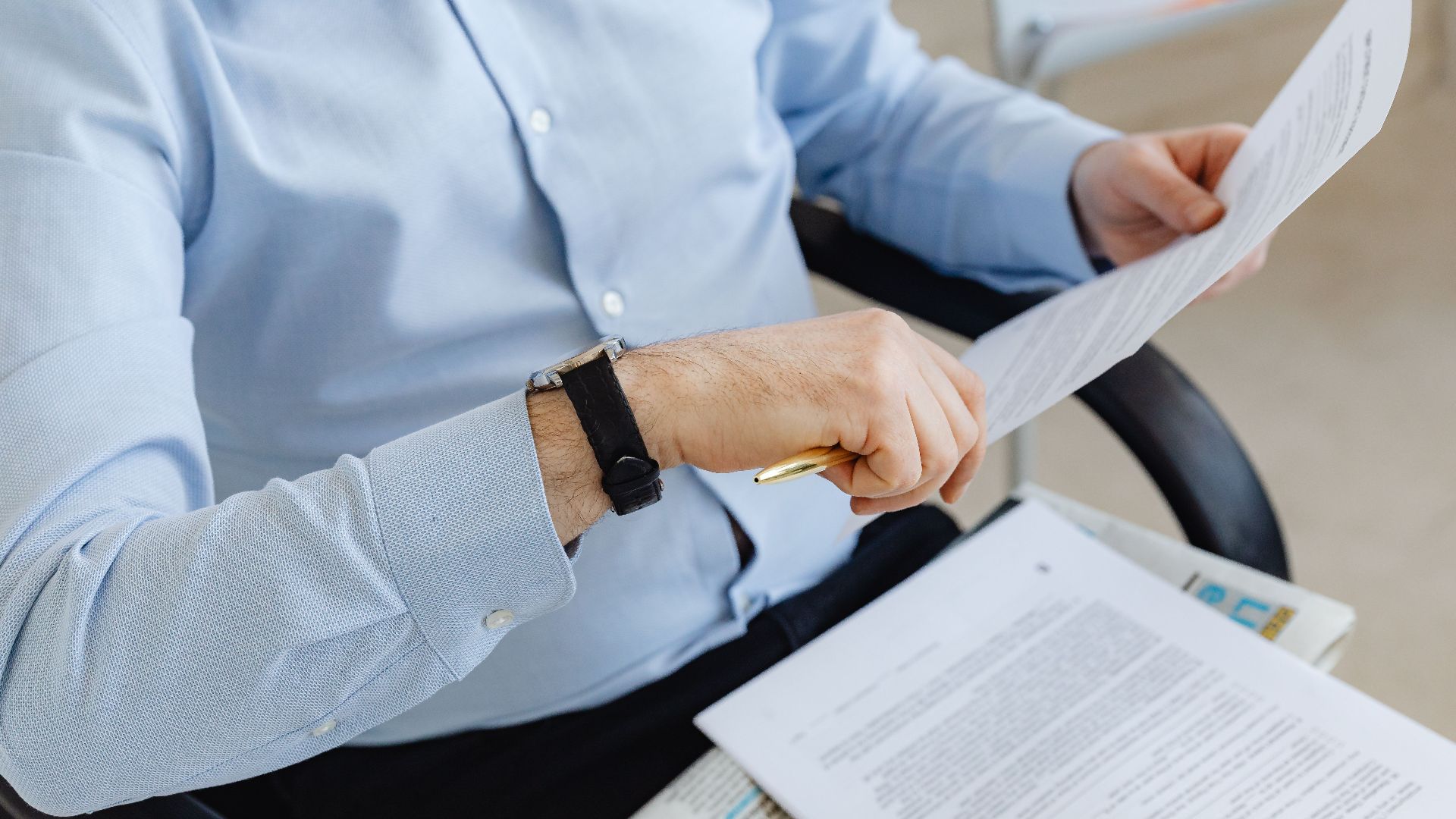 Businessman reviewing papers in office setting, highlighting analysis and attention to detail.