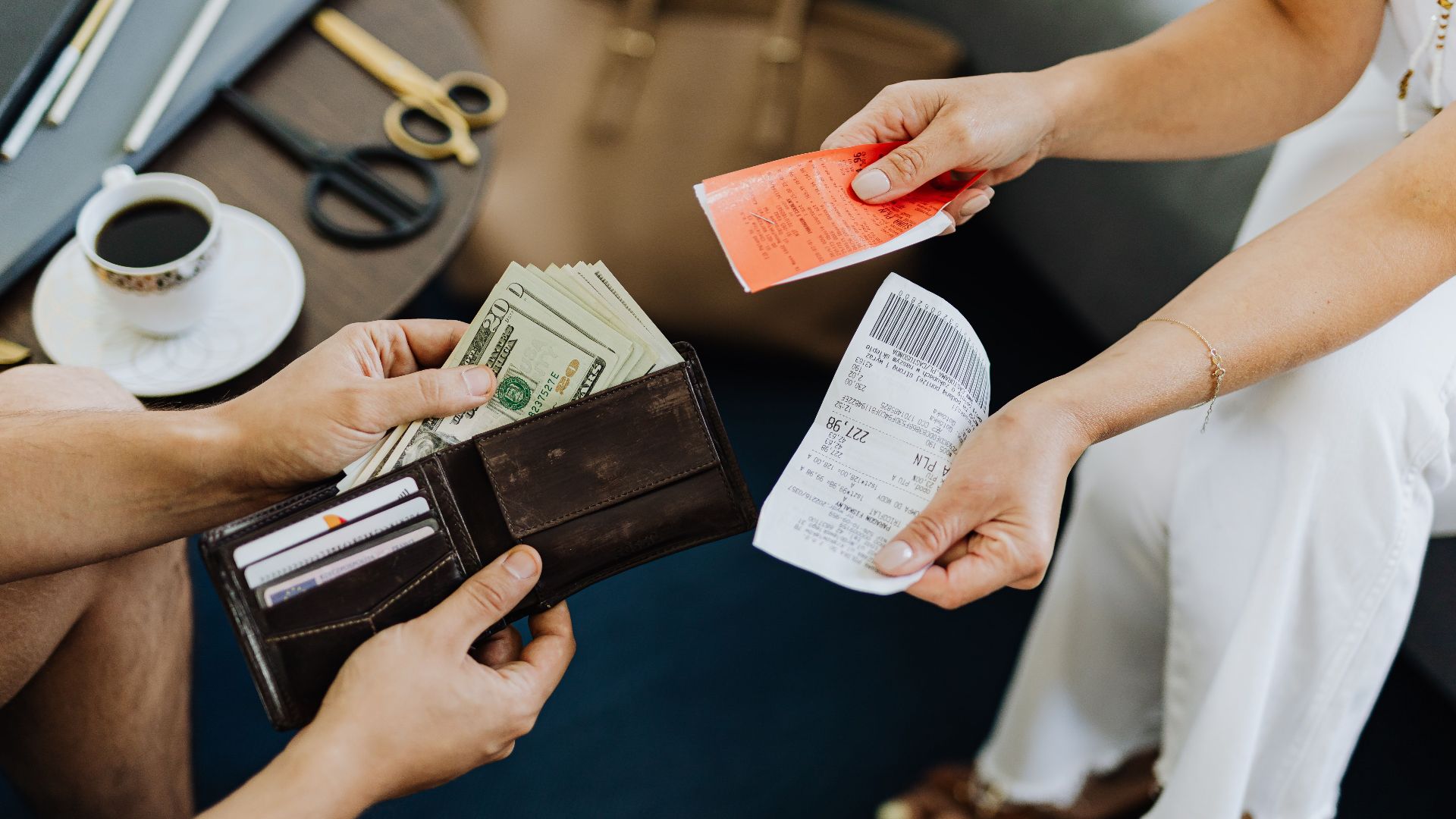 Close-up of a financial transaction involving cash and receipts over a coffee table.