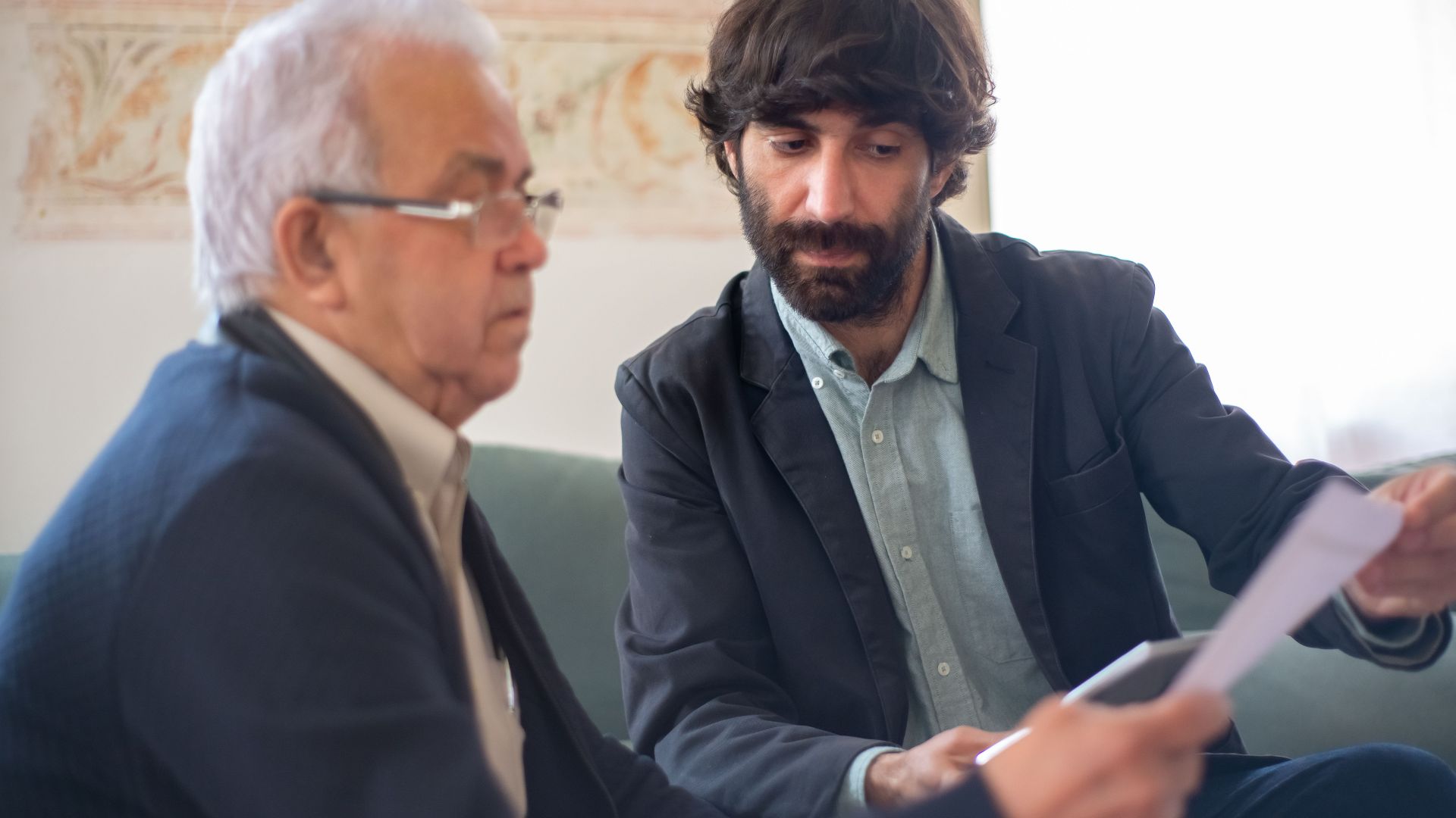 Two men engaged in a business consultation, reviewing documents in a professional setting.