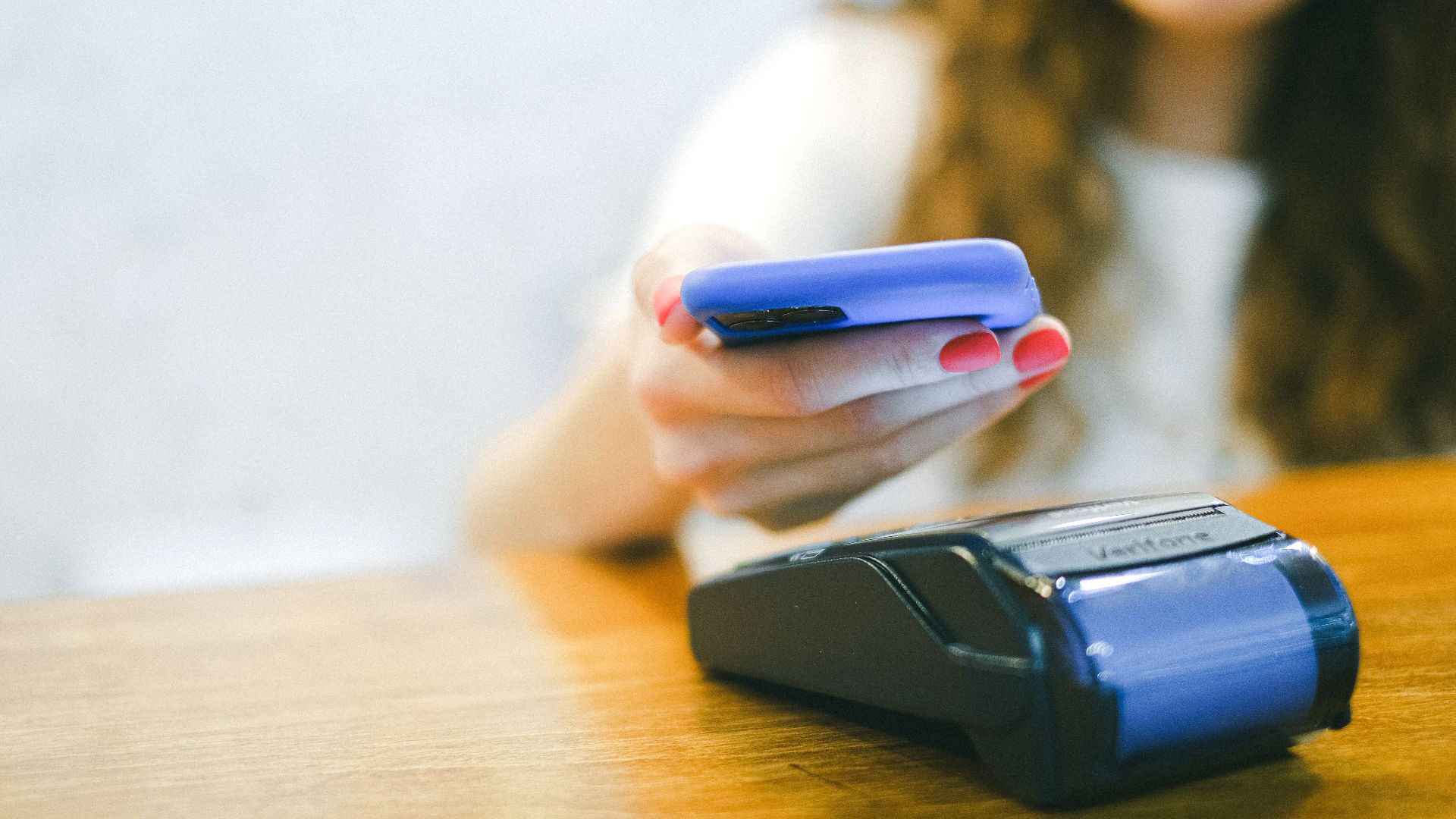 Close-up of a woman making a contactless payment using a smartphone over a card reader