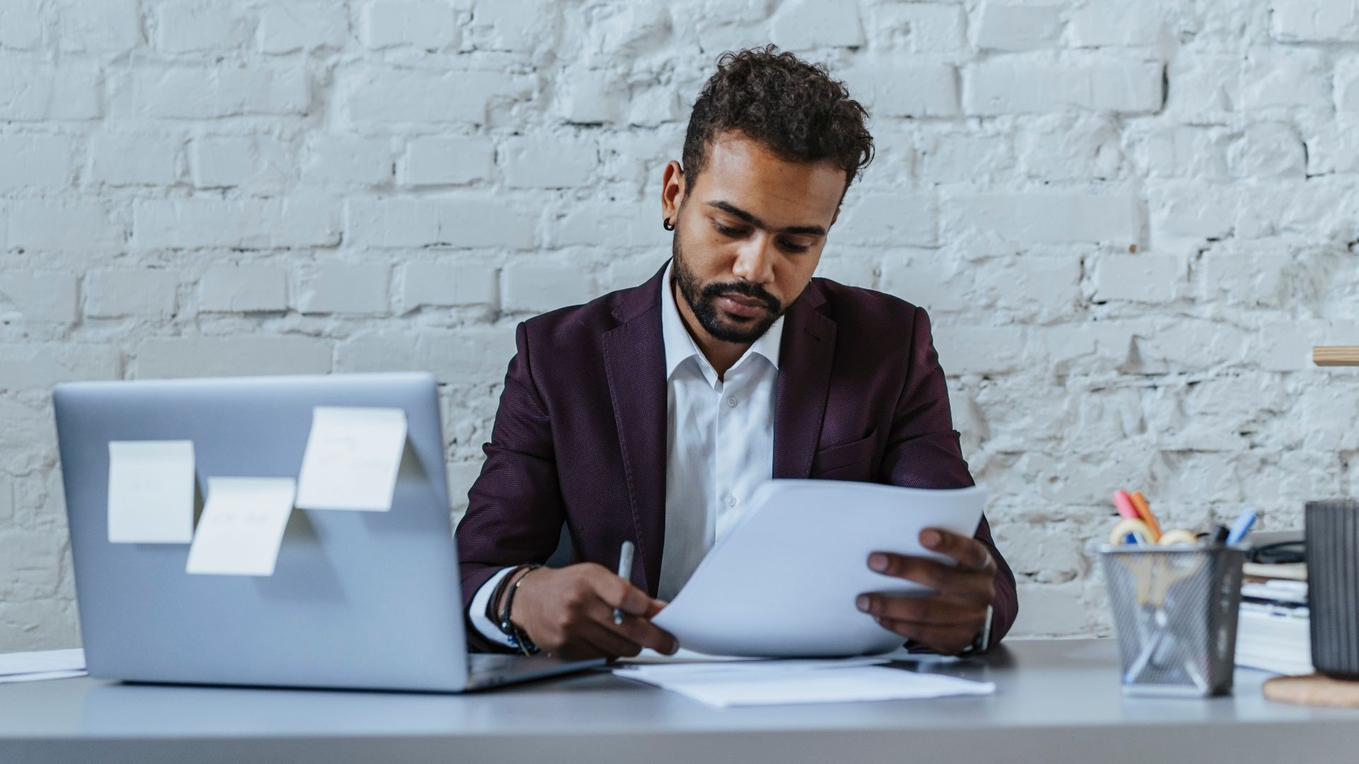 A professional man reviews documents in a modern office setting, focused on his work.
