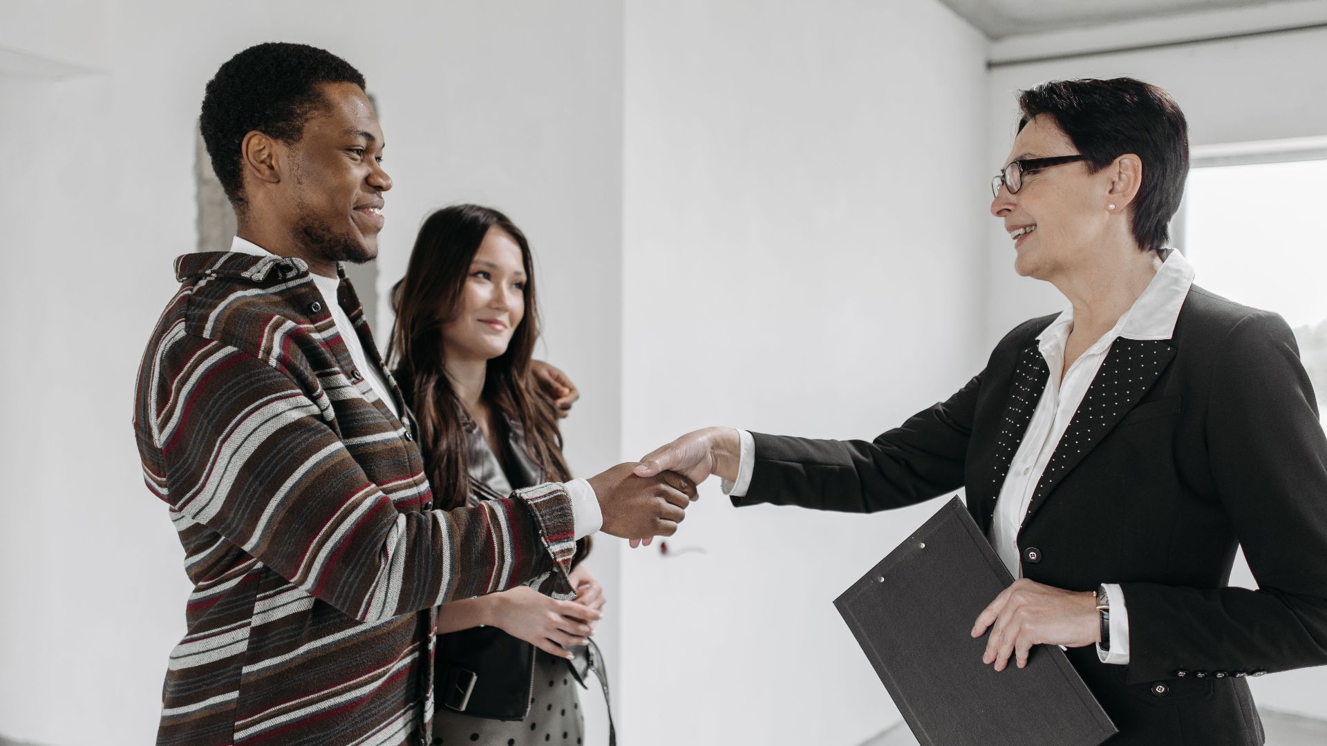 Business professionals shake hands in a modern office, symbolizing a successful deal.