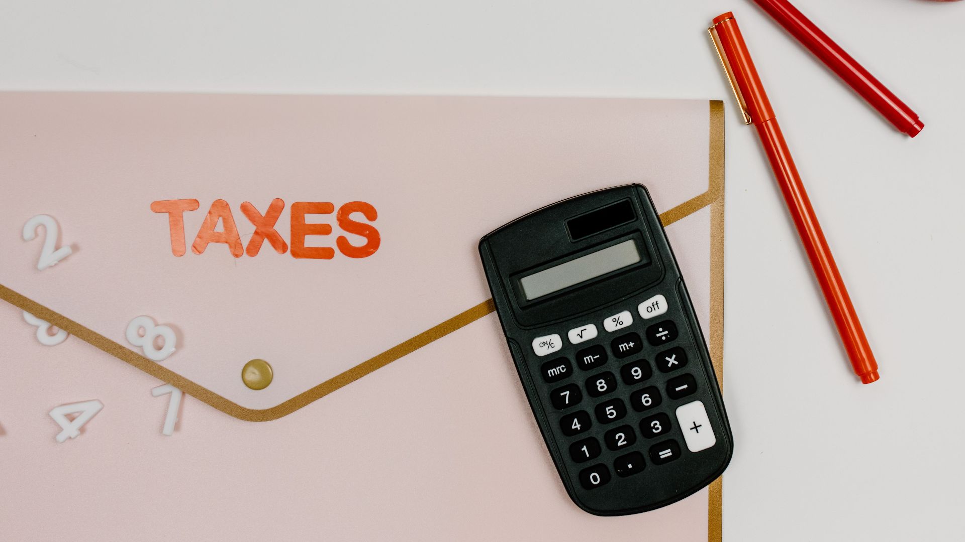 Flat lay image featuring a calculator, pens, and a folder labeled 'TAXES', perfect for finance-related themes.