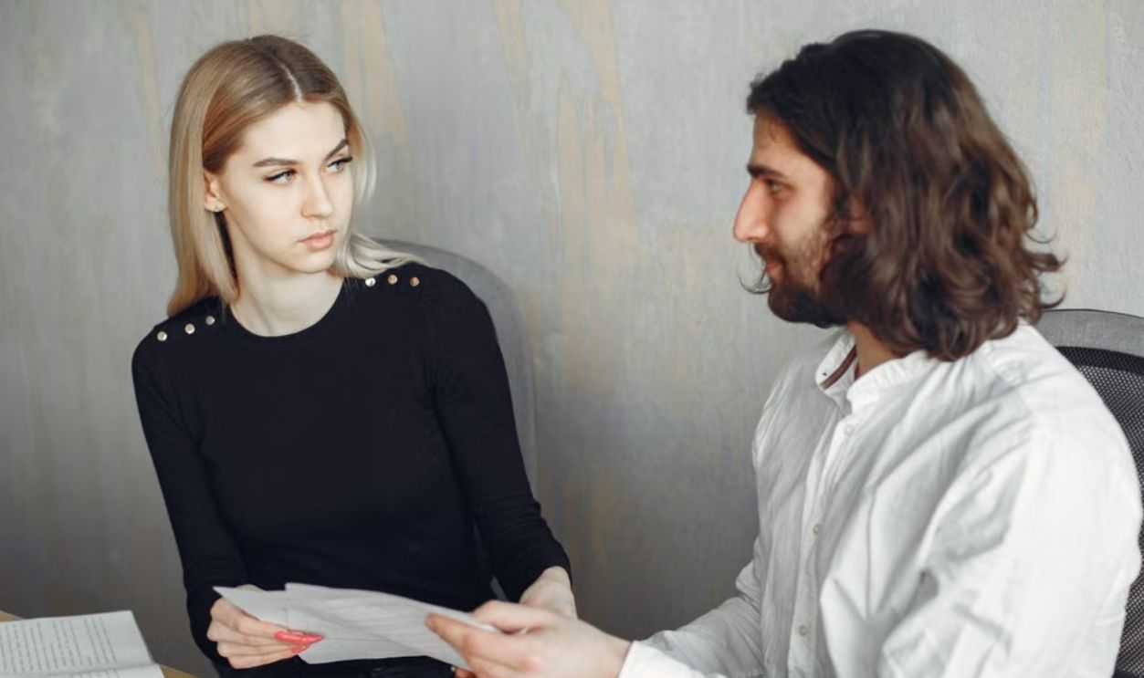 Two colleagues engaged in a focused discussion at the office, sharing documents