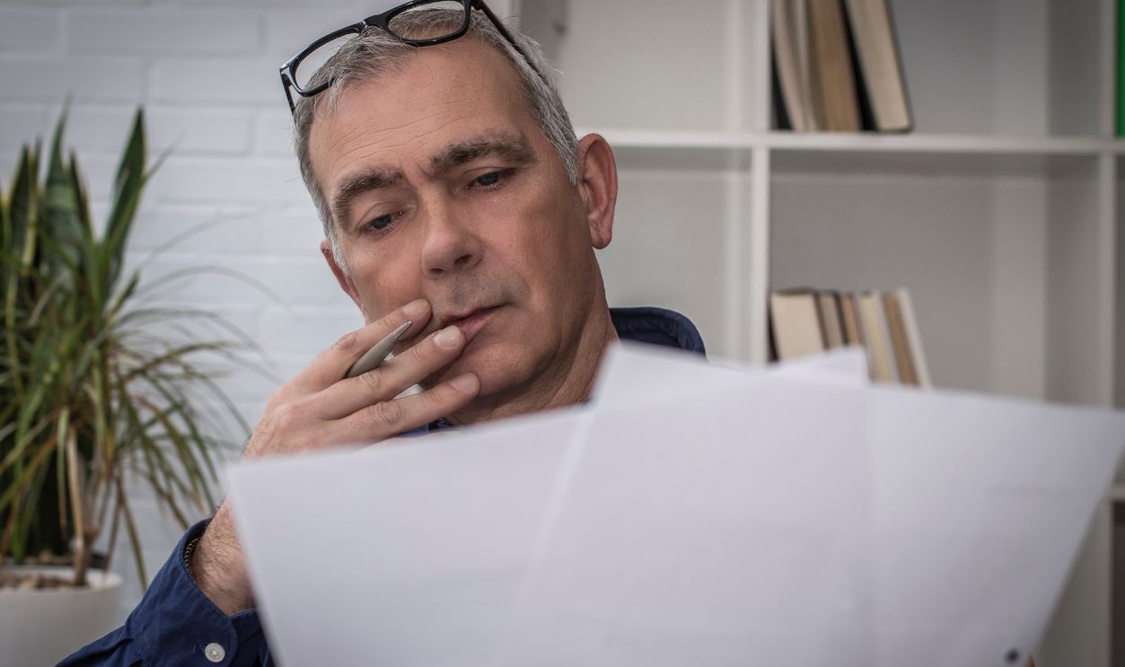 Shutterstock-2416734031, mature man reading documents at his workplace