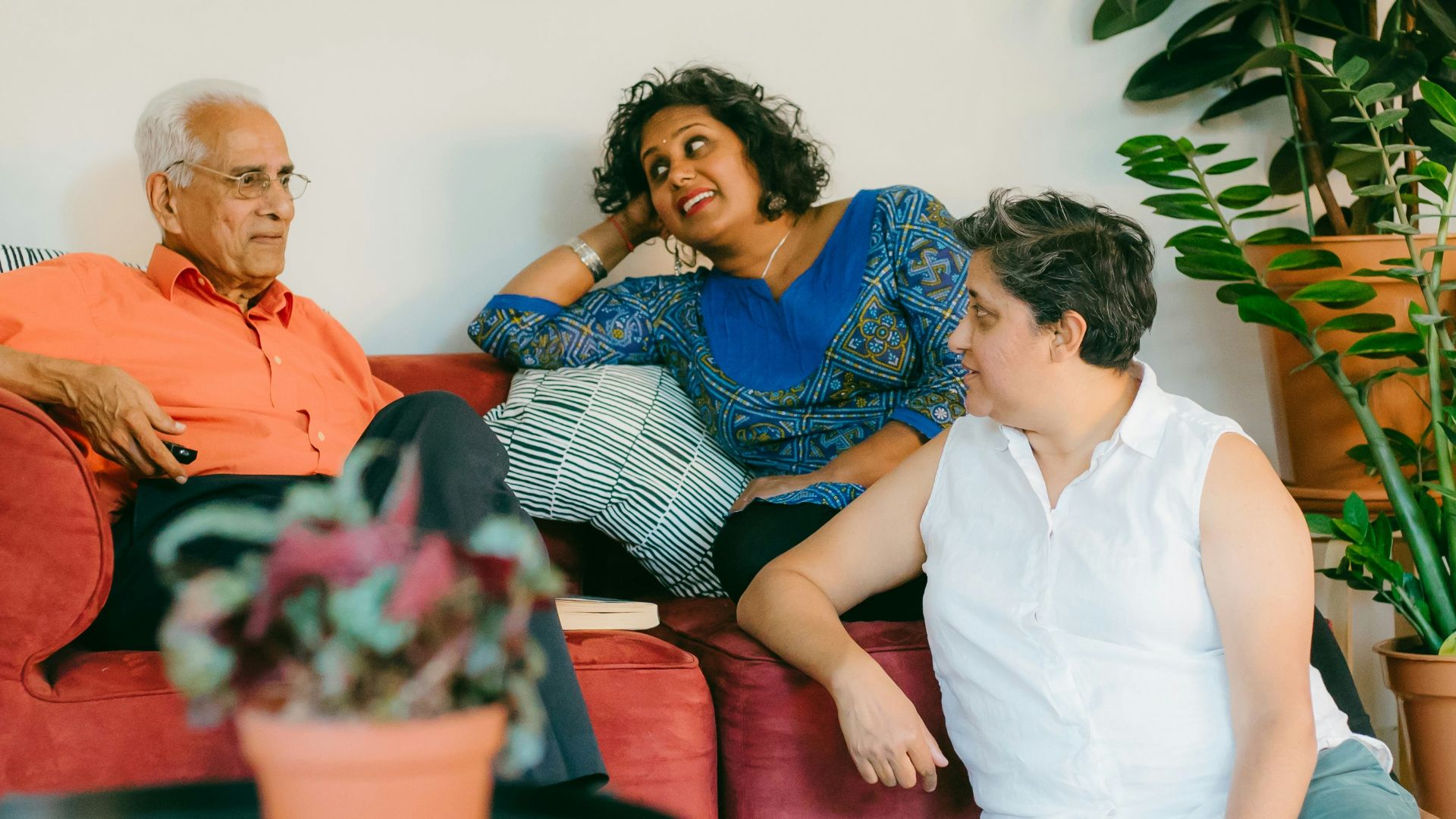 a woman sitting on top of a red couch next to a man