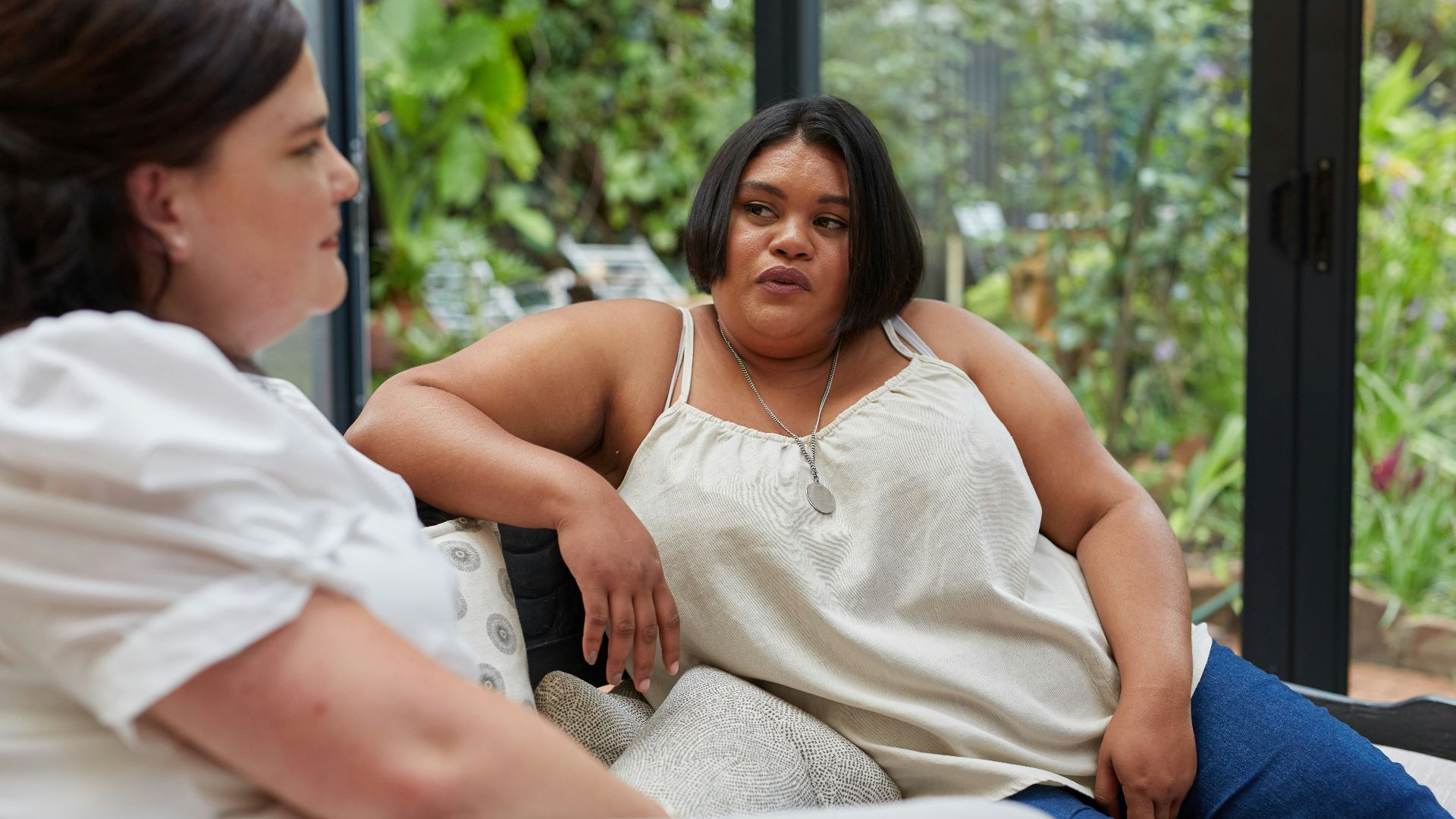 Two women have a conversation on a couch.