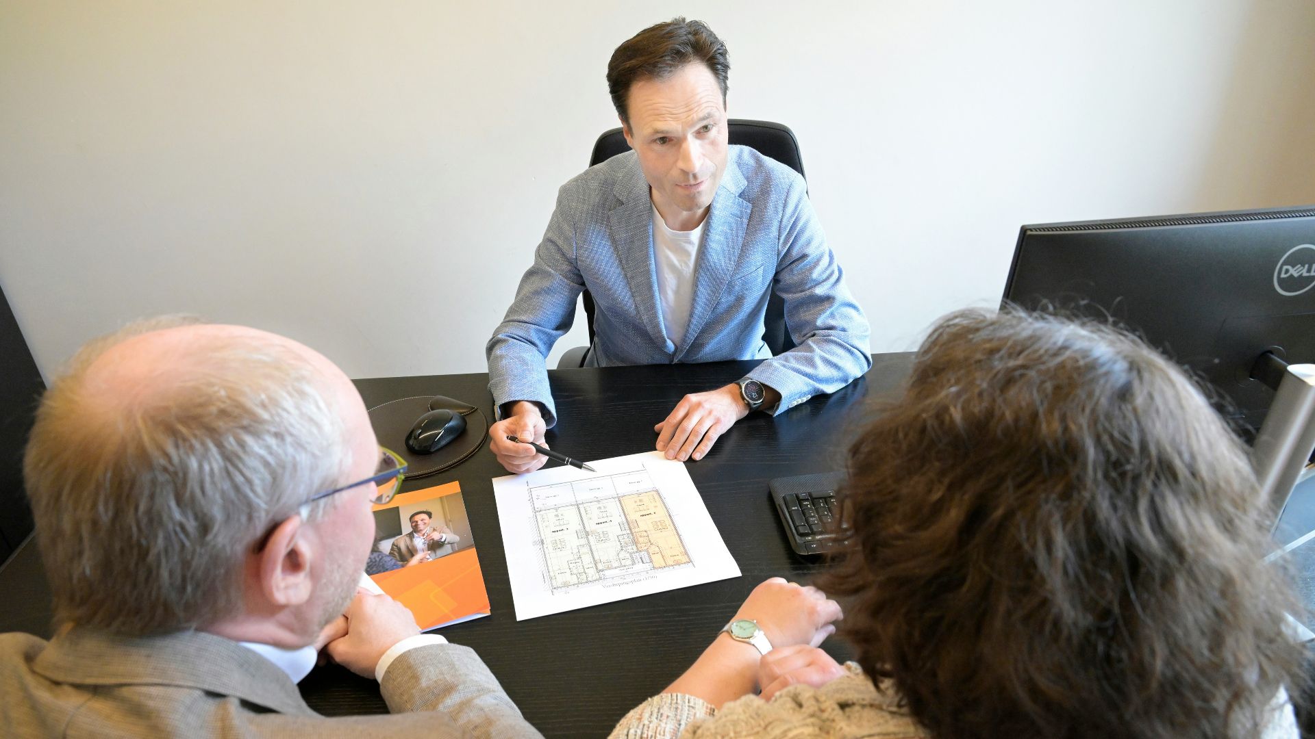 Consultant explains plans to a couple during a business meeting.
