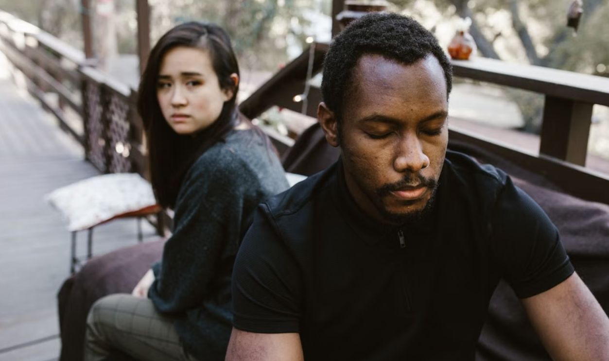 A couple in a serious moment, suggesting conflict or breakup, outdoors