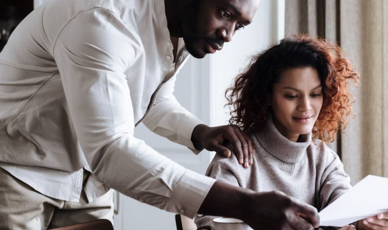 A couple working together at home, reviewing documents with a laptop and coffee