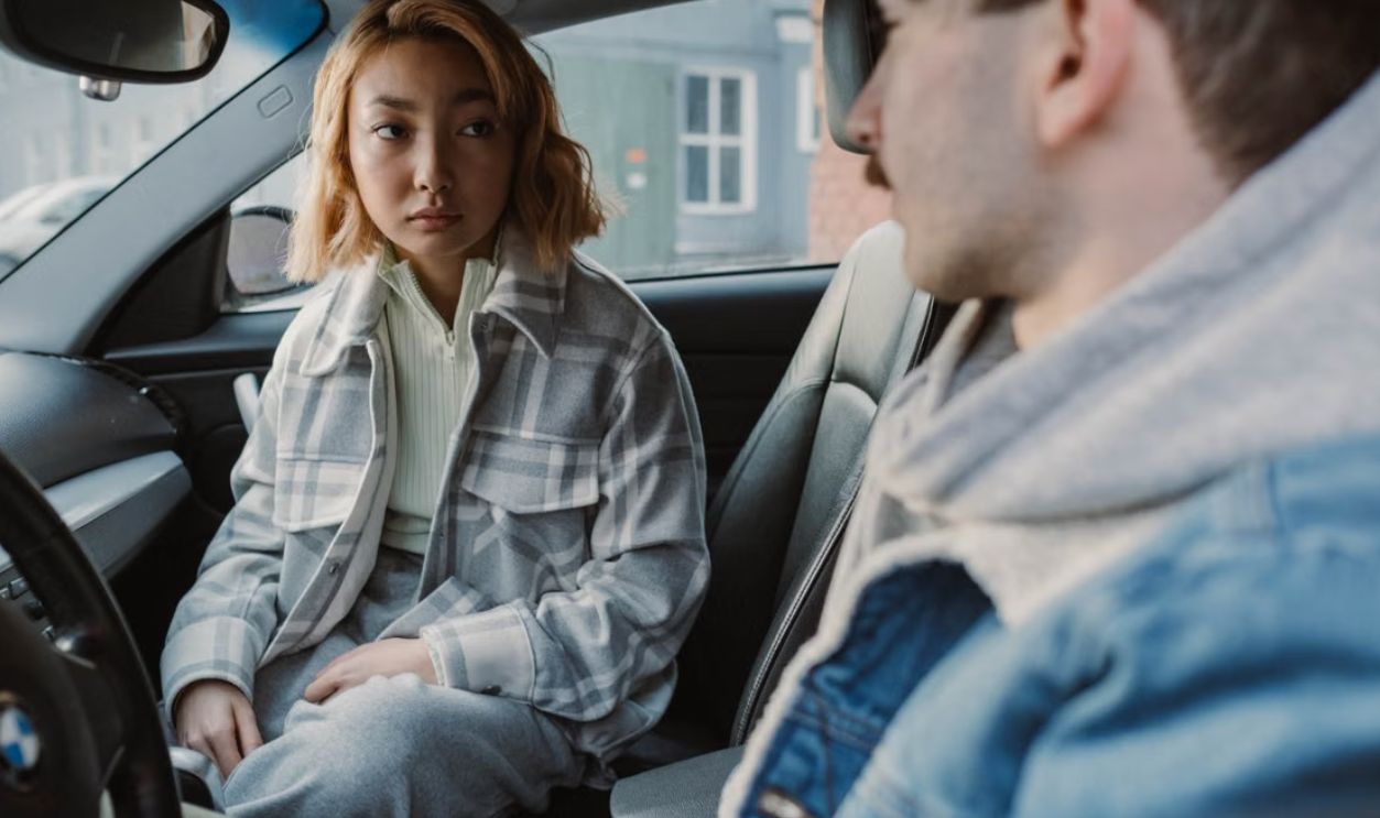 A young couple engaged in a serious conversation inside a parked car, capturing emotional tension